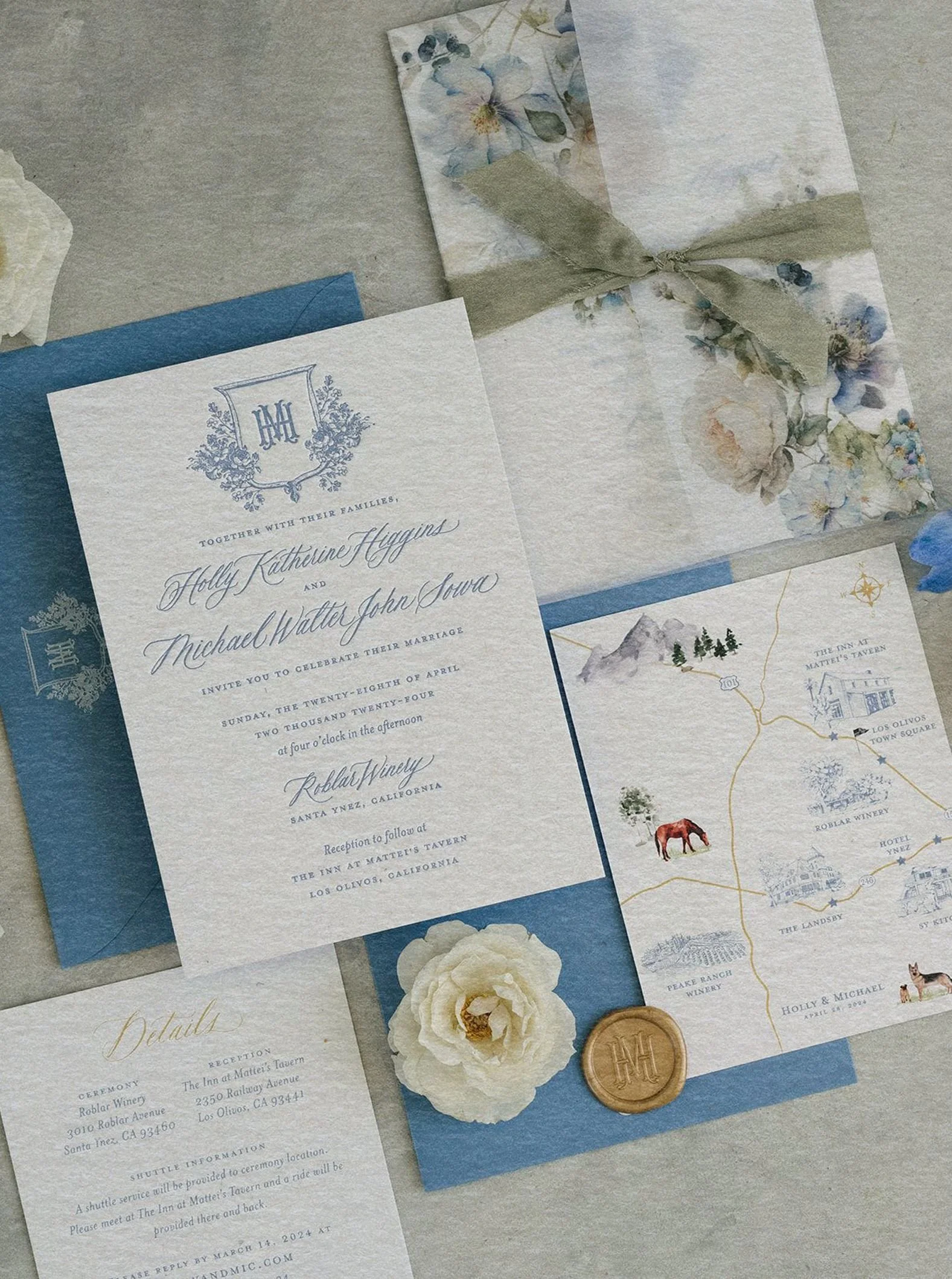 Elegant wedding invitation set featuring blue calligraphy on cream paper, a floral design envelope, a custom map, and a wax seal, conveying a romantic tone.