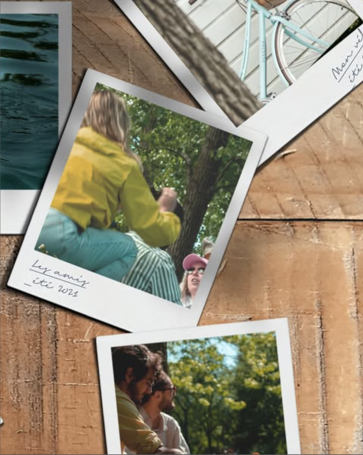 Three printed photographs of people outdoors on a wooden surface. The middle photo shows a person in a yellow jacket and striped pants seen from behind, sitting on a tree branch. The bottom photo shows two people sitting in a sunny park with green trees. The top photo shows a close-up of water in a container.