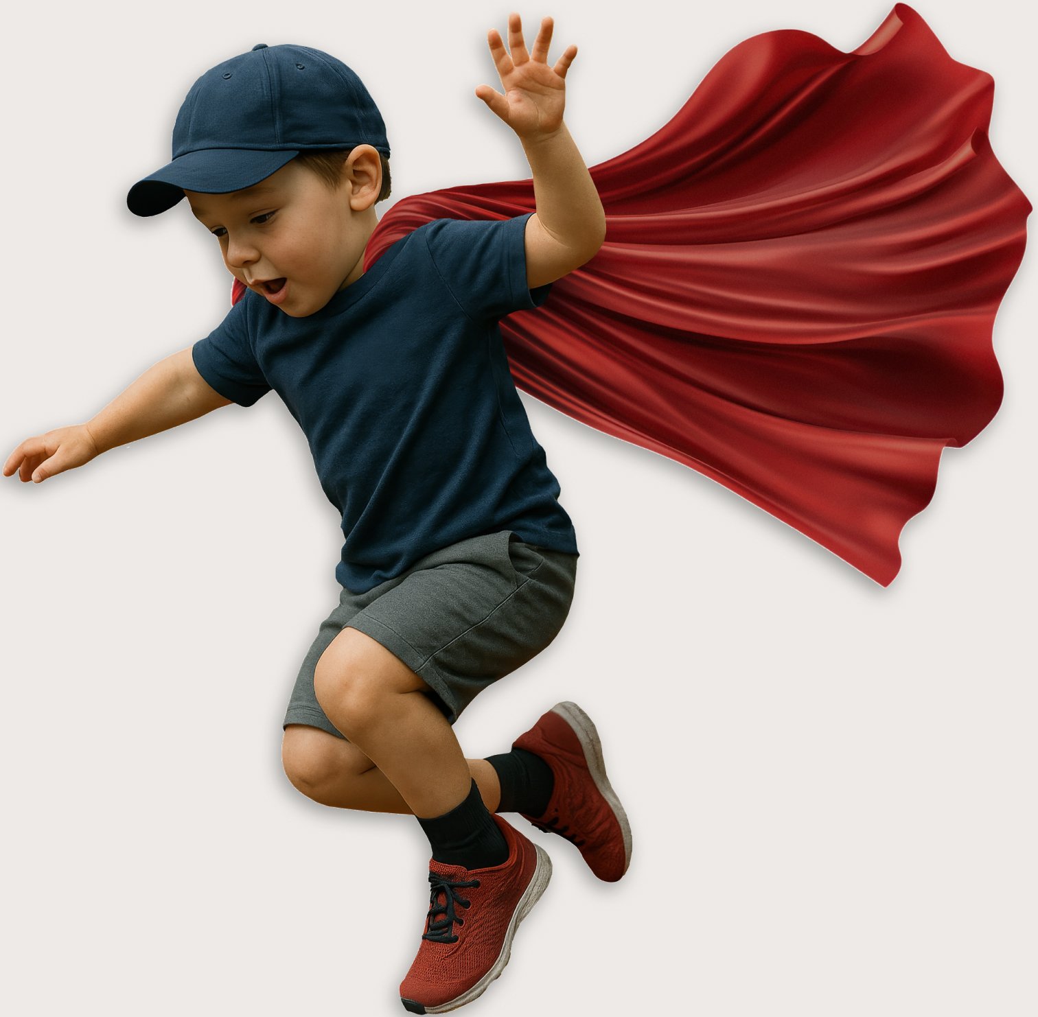 Young boy wearing a superhero costume with a red cape, navy blue shirt, gray shorts, red sneakers, and a navy cap, appearing to fly or jump.