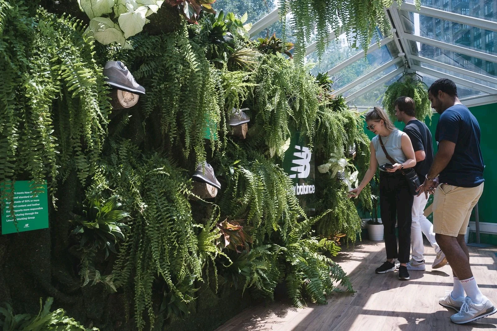 People shopping for New Balance sneakers inside a plant-covered store.