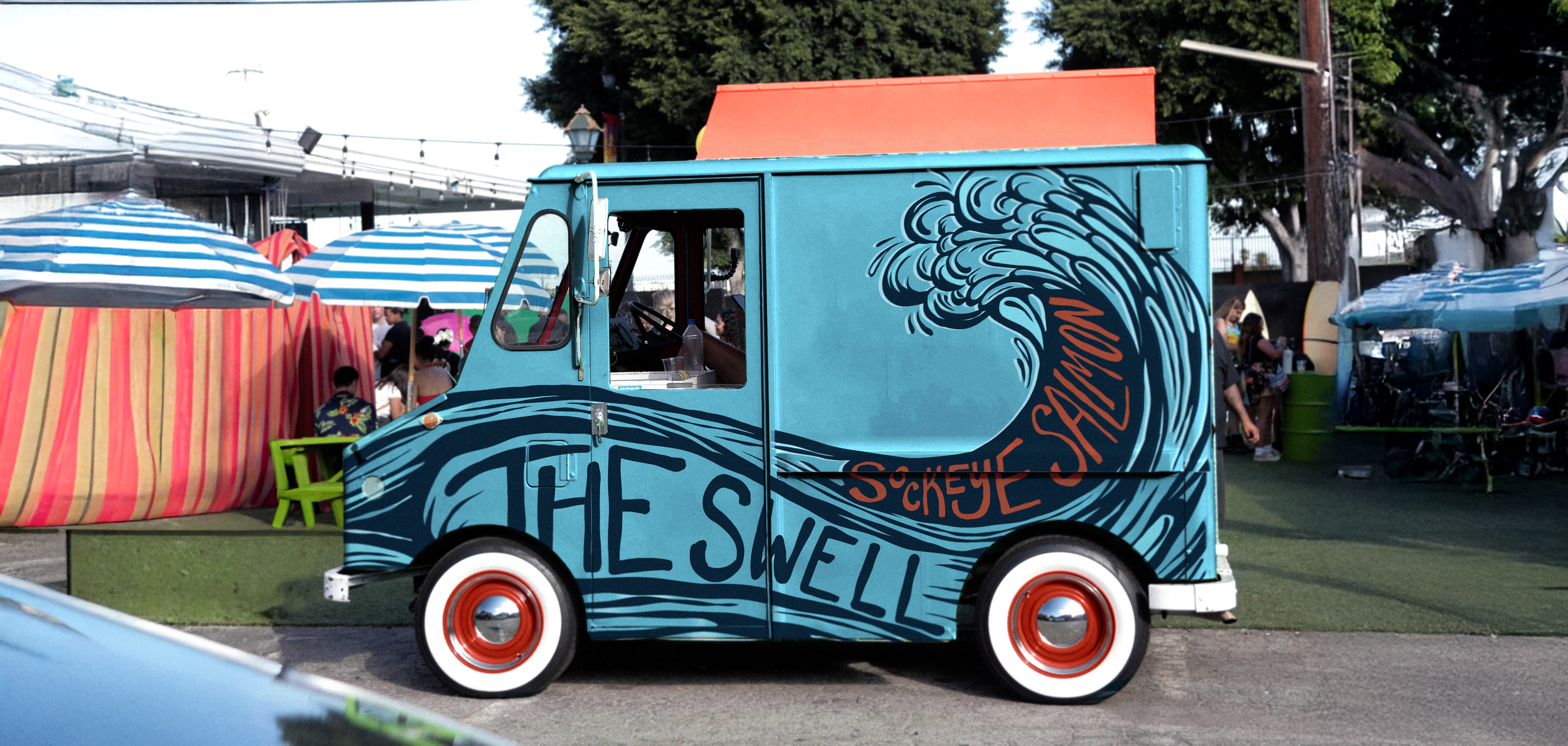 Blue food truck with ocean wave design and 'The Swell' text, parked at an outdoor event with umbrellas and people in the background.