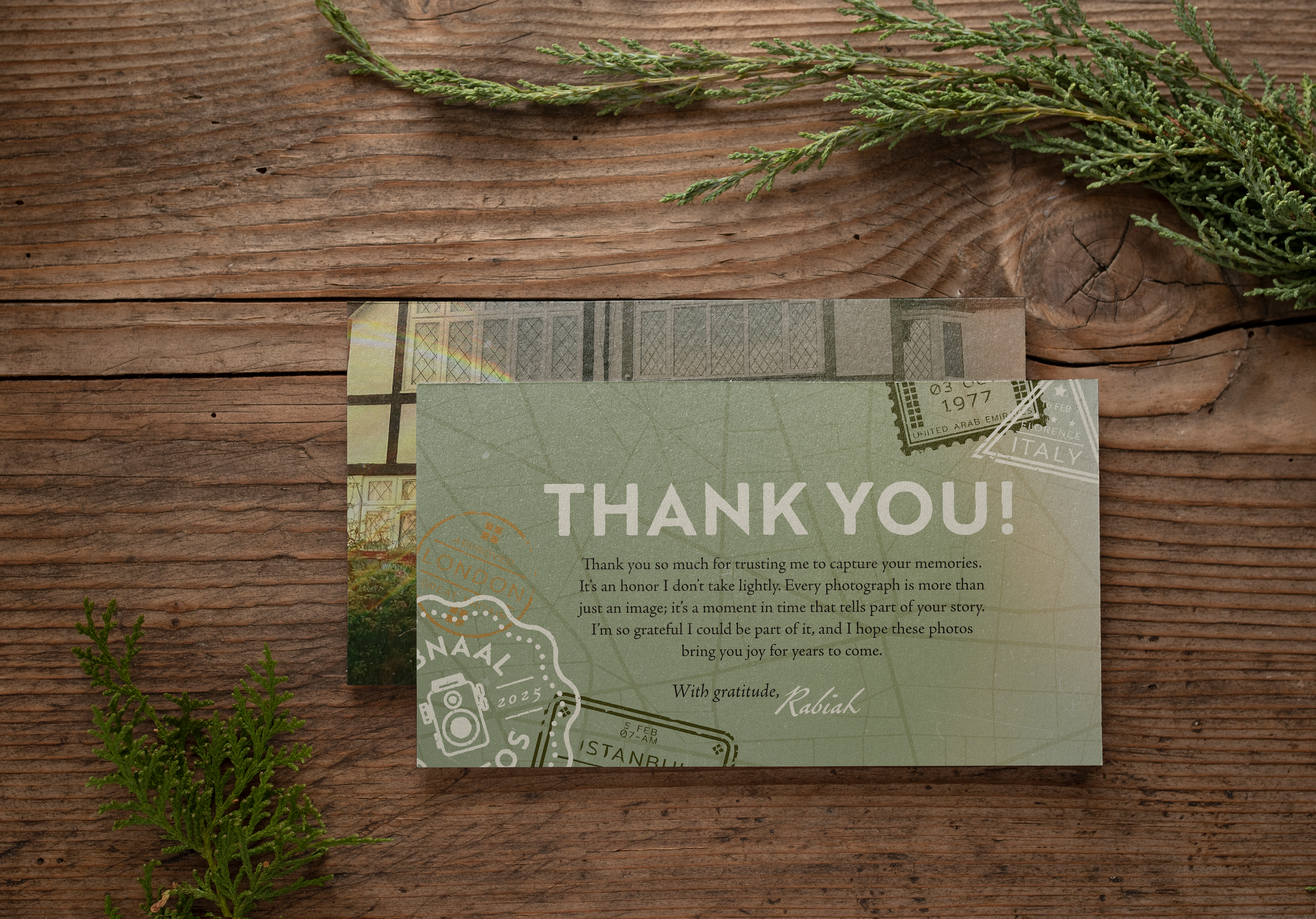 A thank you card on a wooden surface with green foliage around it. The card has travel-themed graphics and a message expressing gratitude.