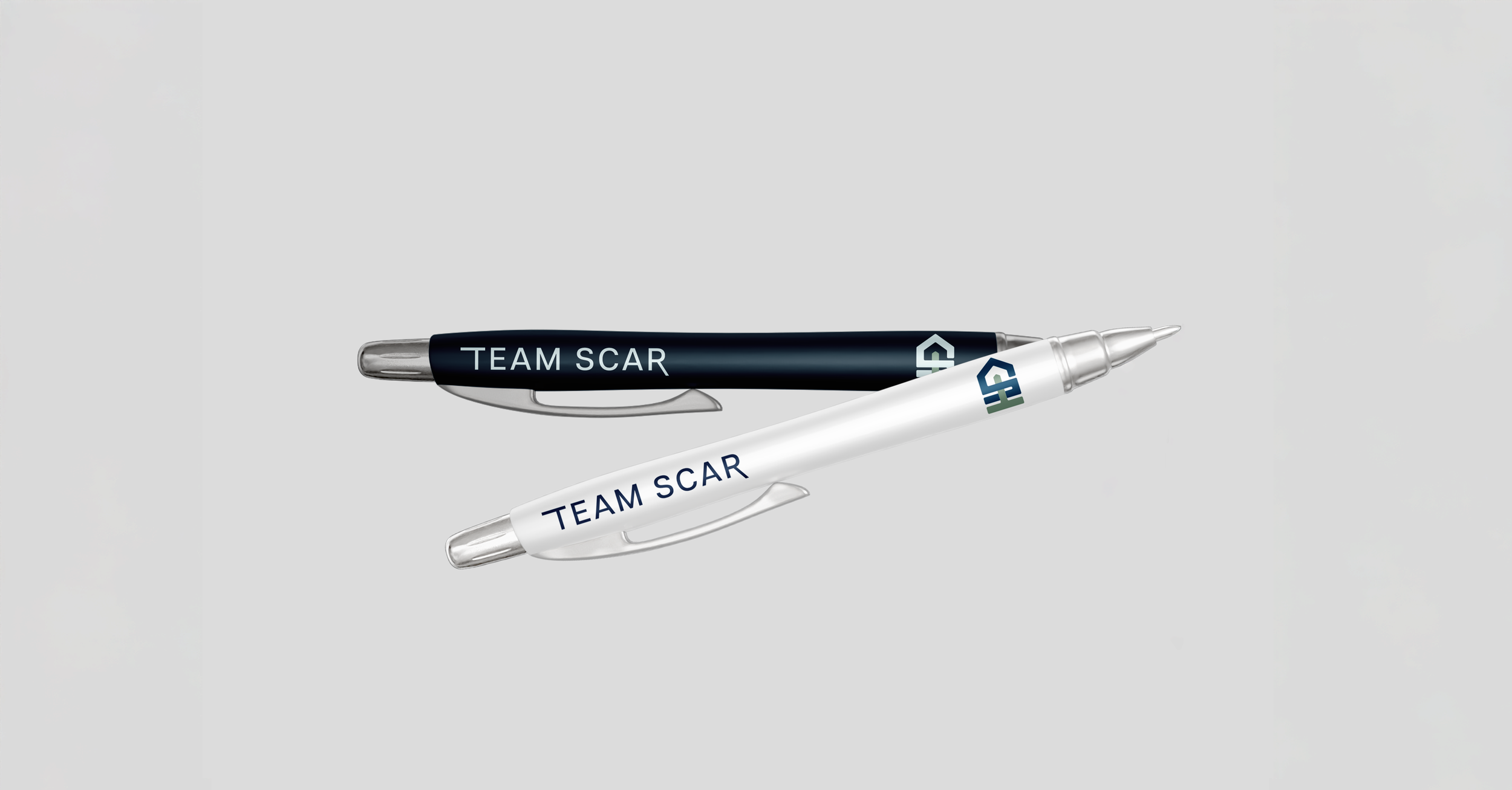Two pens, one black and one white, both with 'TEAM SCAR' written on them, are crossed over each other on a plain background.