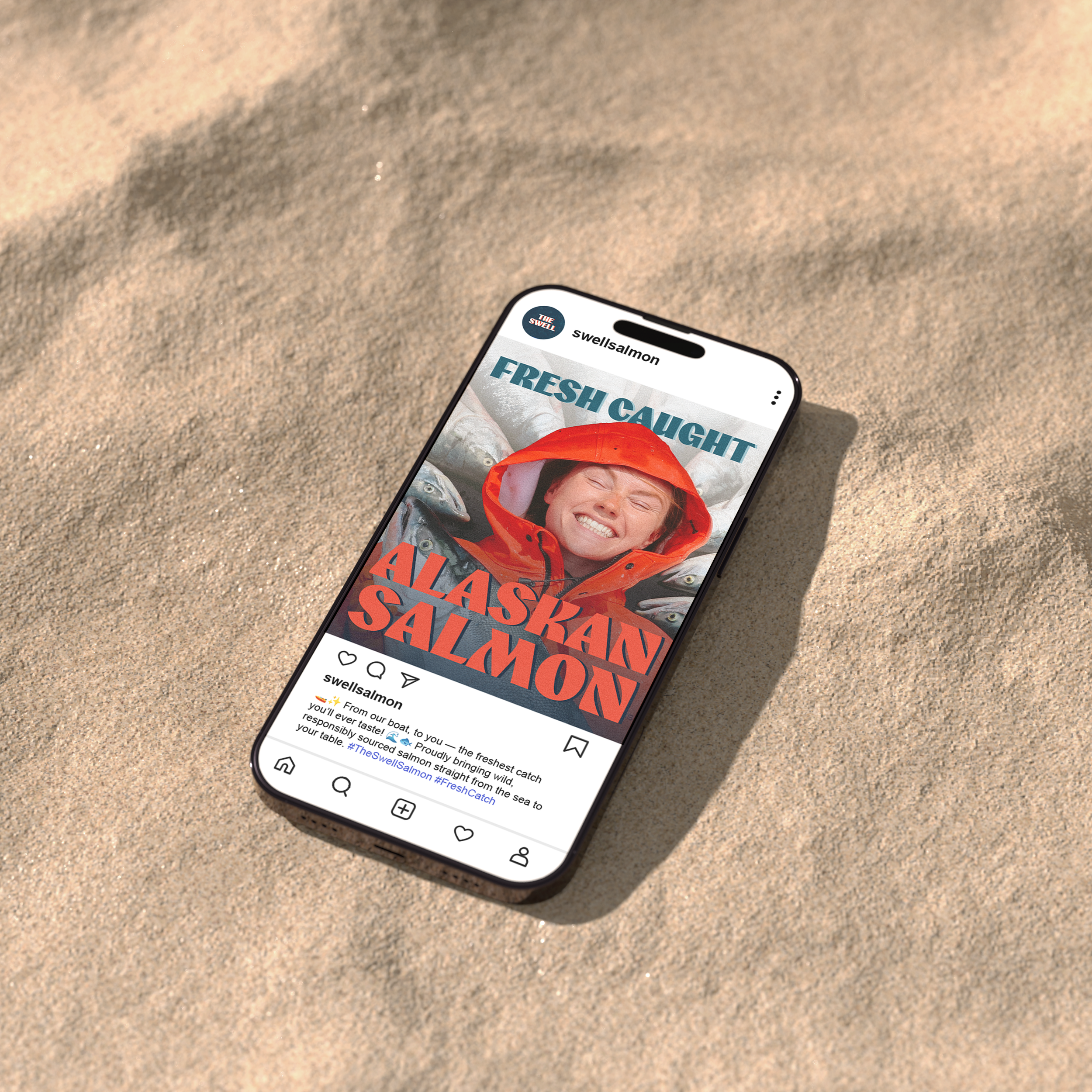 A smartphone on a sandy surface displaying an Instagram post about Alaska salmon, showing a smiling woman in a red jacket surrounded by fish.