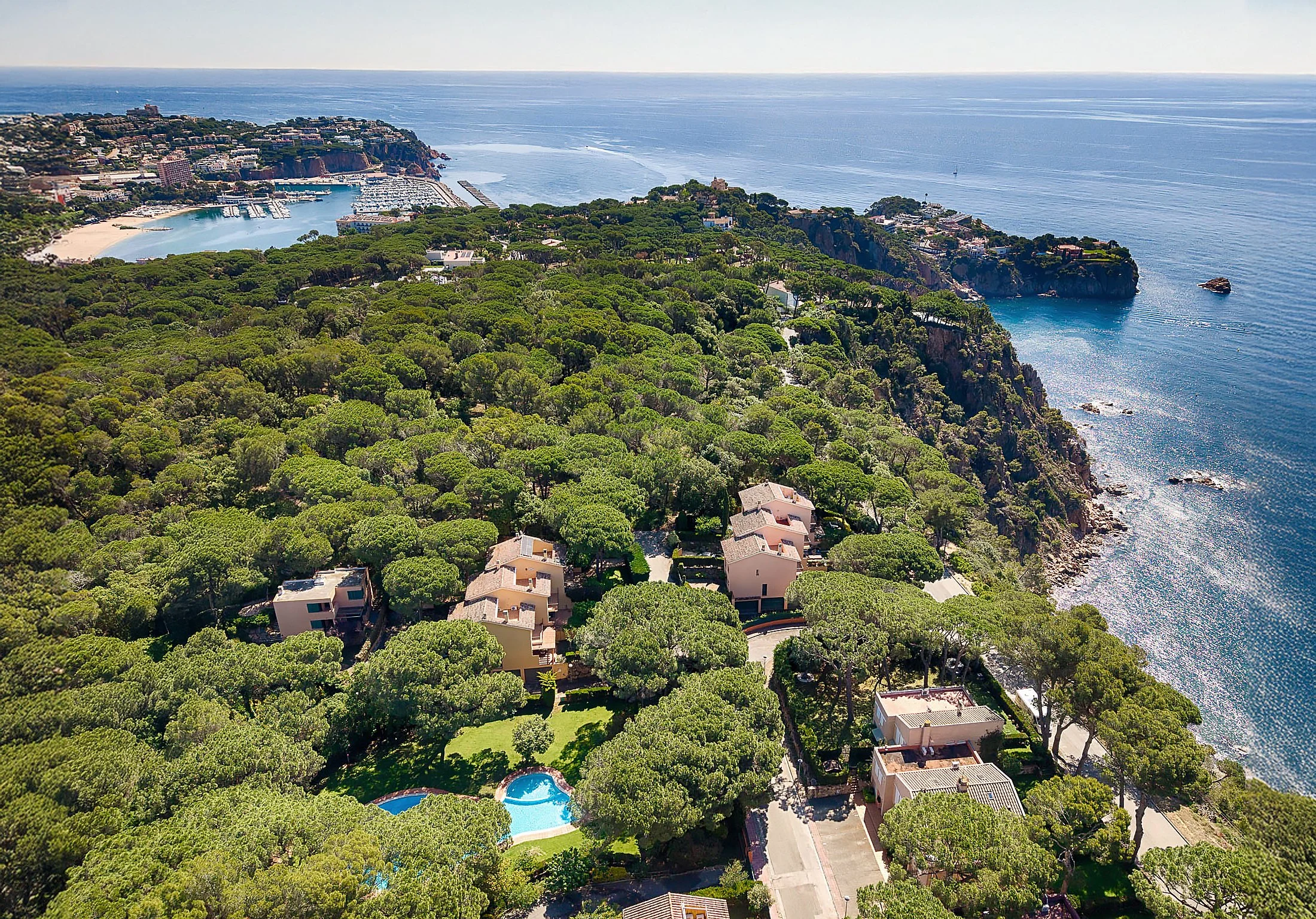 Aerial view of a coastal city of Sant Feliu de Guixols In Costa Brava, Spain, in the forest. House near the sea, and a marina with yachts and boats, overlooking the ocean.