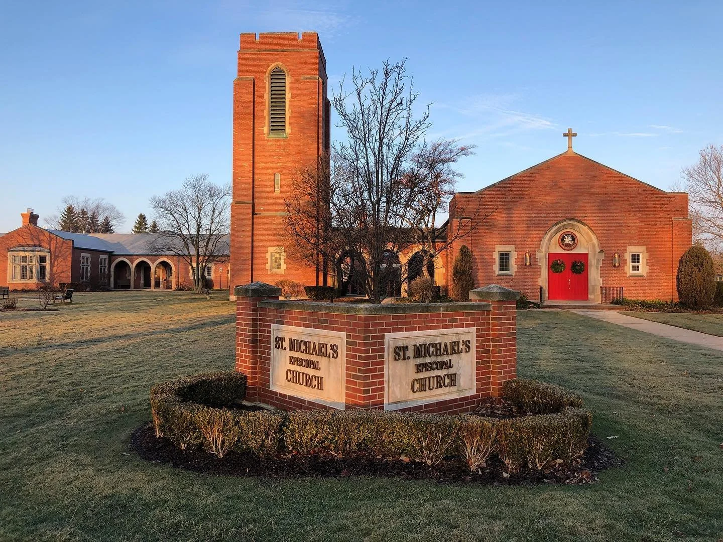 A red brick church or cathedral with gothic architectural features, including pointed arches and large windows, under a blue sky with some clouds.