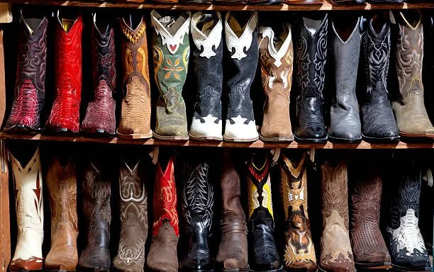 Two shelves of cowboy boots in various colors and styles.