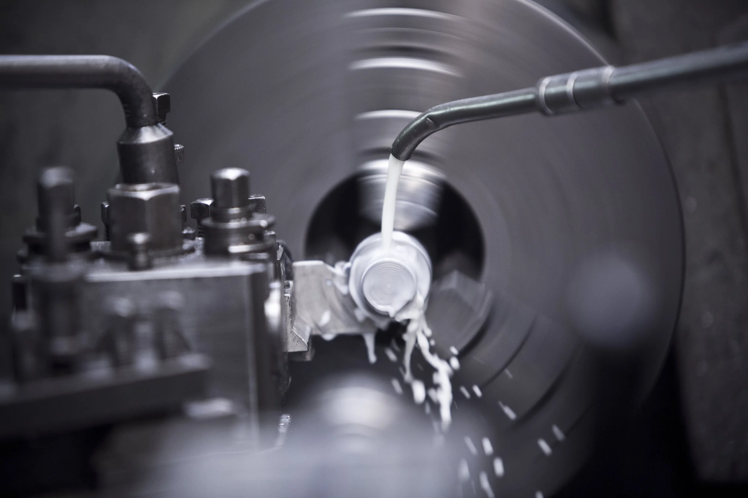 A metal manufacturing process with a machine pouring white liquid metal into a rotating mold.
