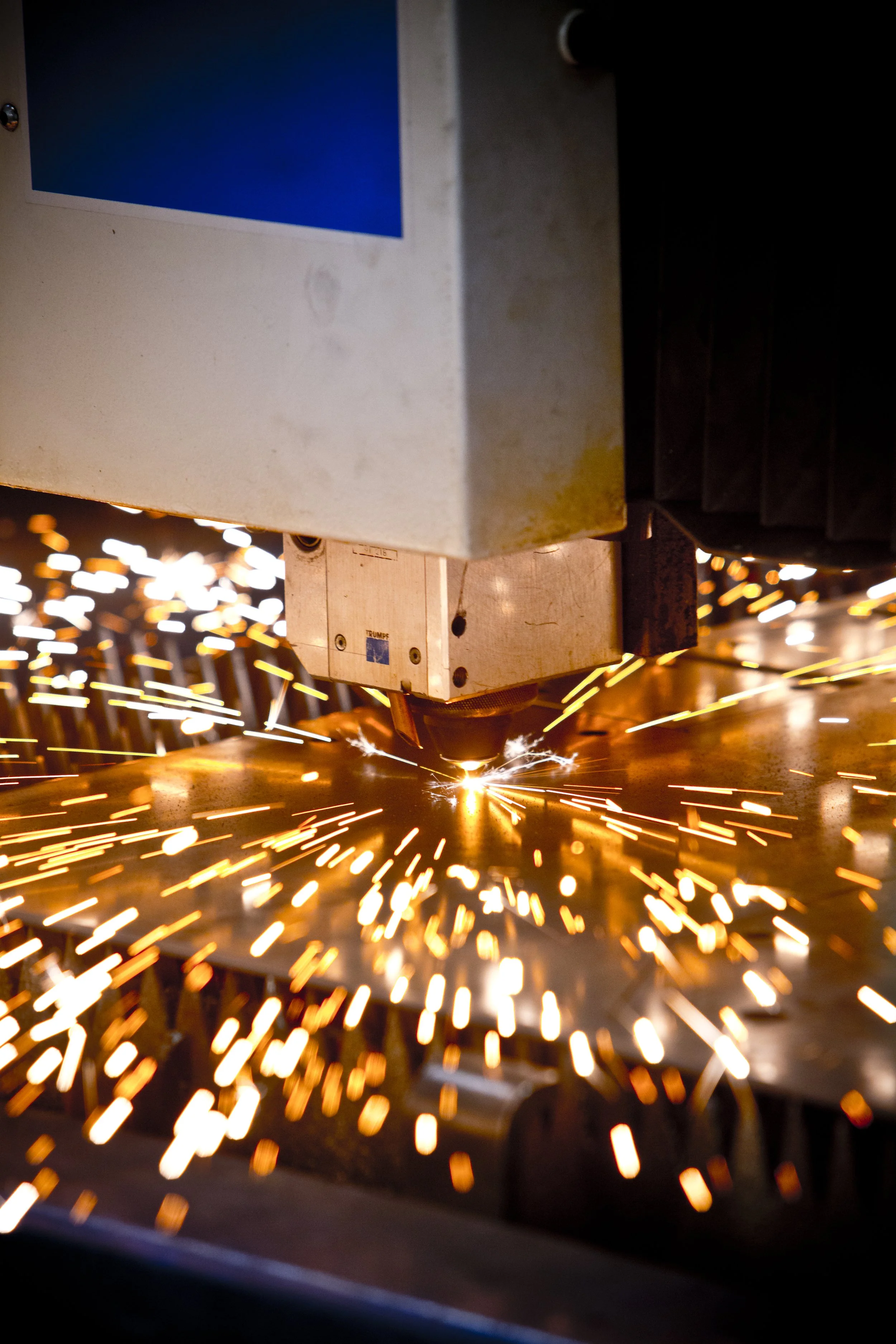 A laser cutter welding metal, with sparks flying around.