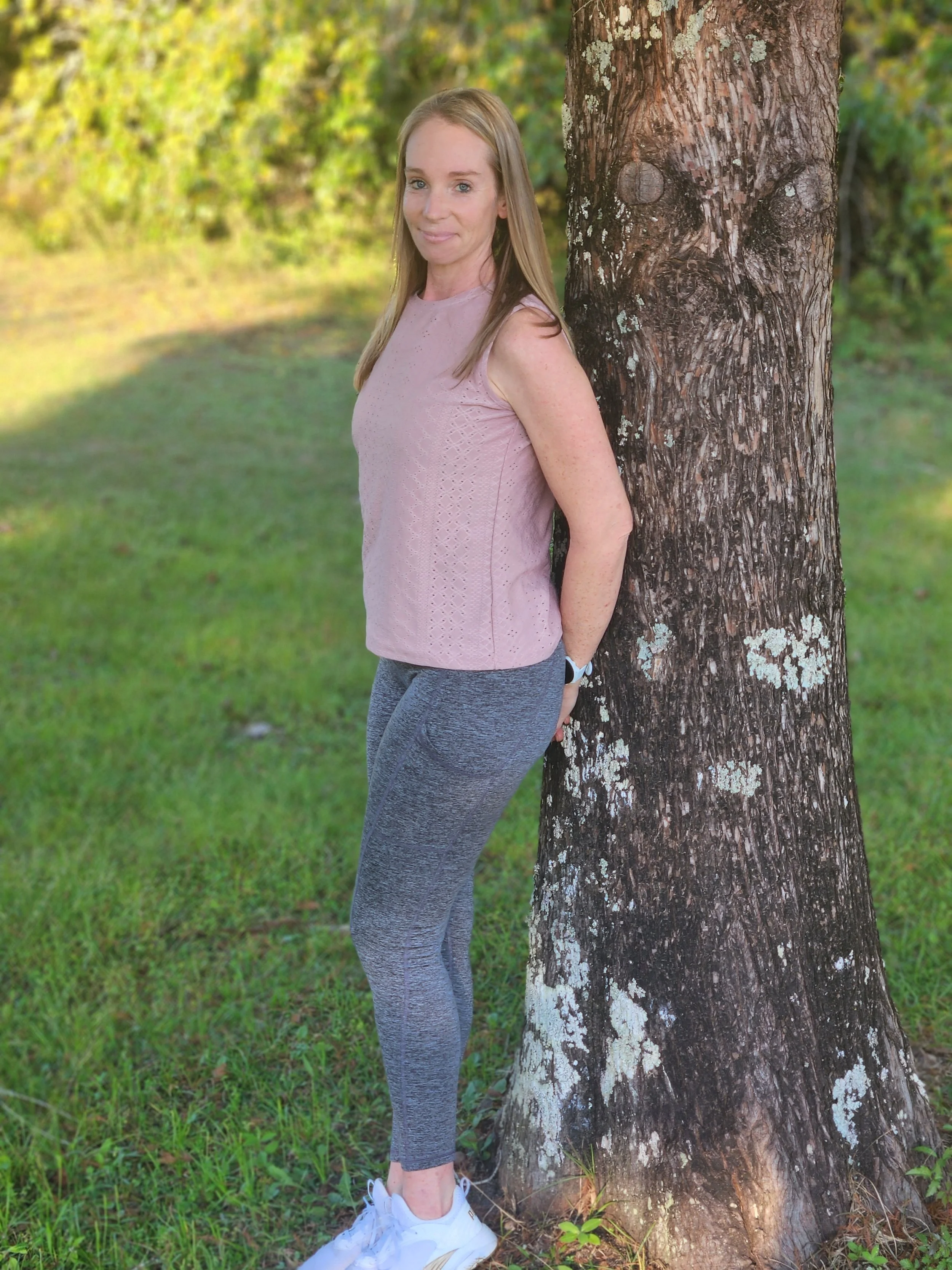 Dana Jordan, professional organizer, smiling outdoors next to a tree, wearing a relaxed outfit.