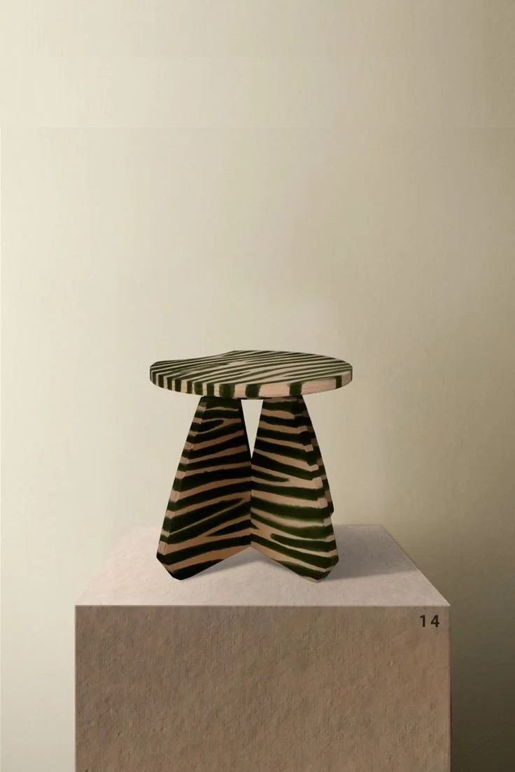 A small black and white striped stool with a round top and triangular legs, placed on a pedestal marked with the number 14.