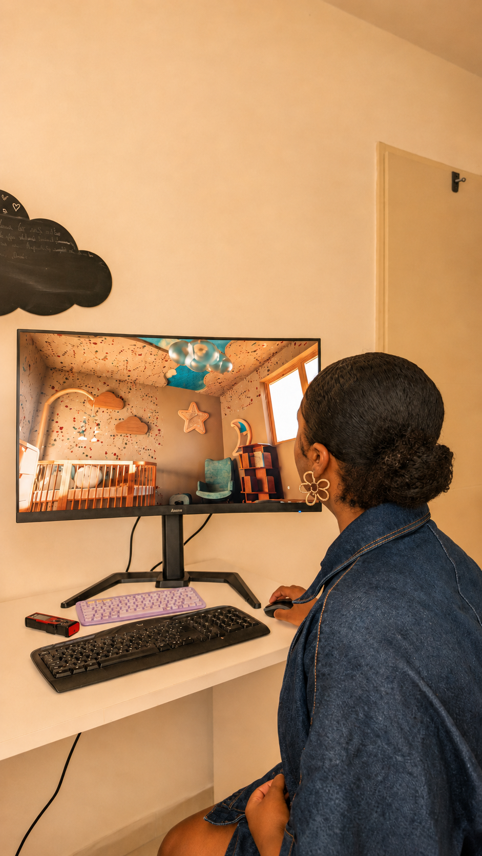 Une femme regarde un écran d'ordinateur affichant une pièce pour bébé décorée de couleurs vives et d'éléments ludiques.