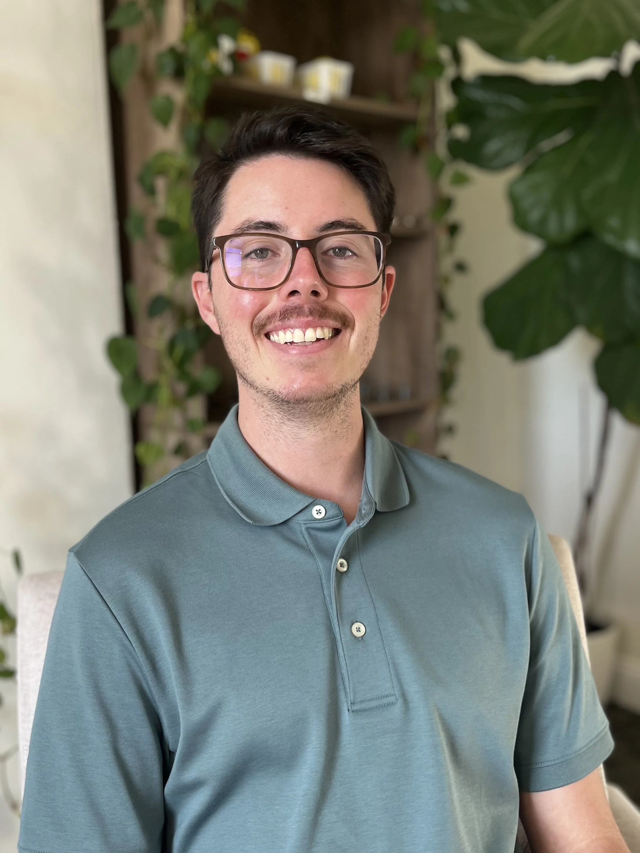A therapist in Santa Barbara smiles in a green shirt while treating addiction and relationship issues