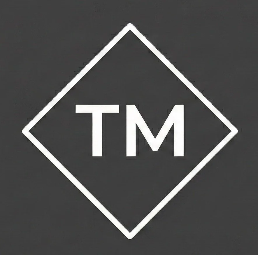 Un logotipo con las letras 'TM' en blanco dentro de un cuadrado inclinado en un fondo gris oscuro.
