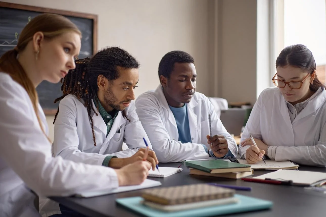 Medical students sitting a table taking notes during a lecture.