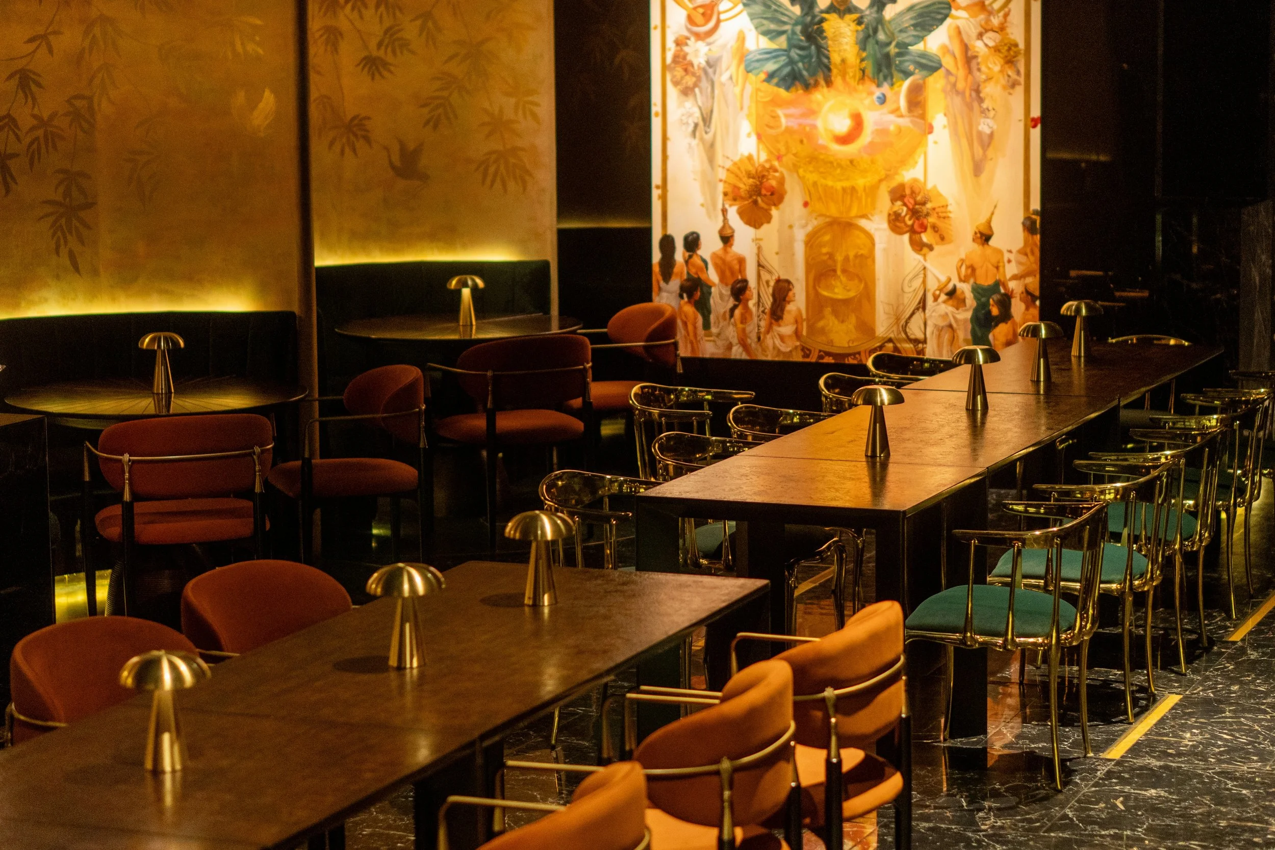 Elegant restaurant interior with metallic and wooden furnishings, polished marble flooring, and warm ambient lighting creating a refined dining atmosphere.