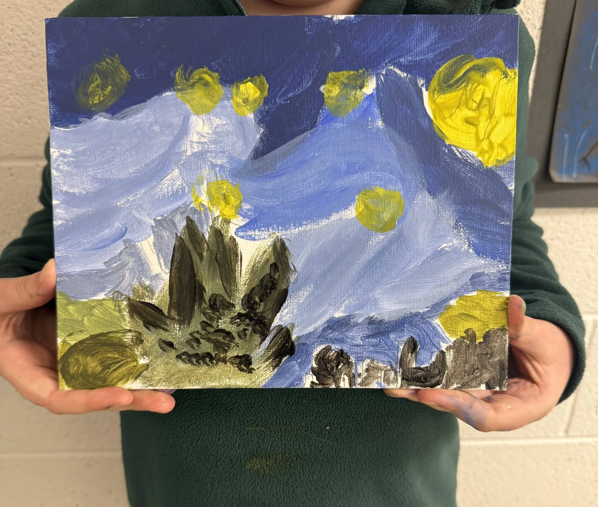 Child holding a painting of a mountain landscape with a blue sky and swirling clouds, with yellow circles representing the sun, and dark trees in the foreground.