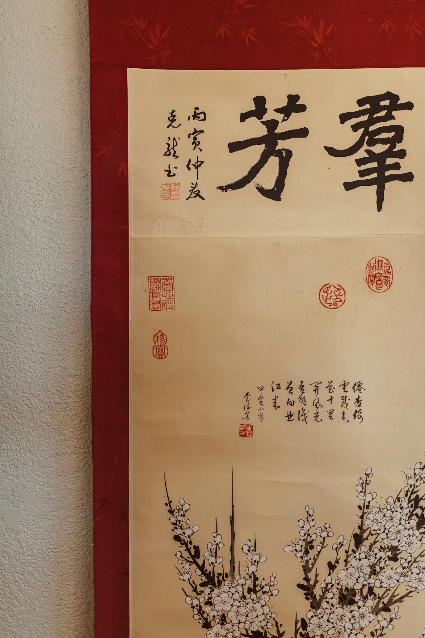 A traditional Chinese scroll painting featuring calligraphy and a plum blossom branch at the bottom.