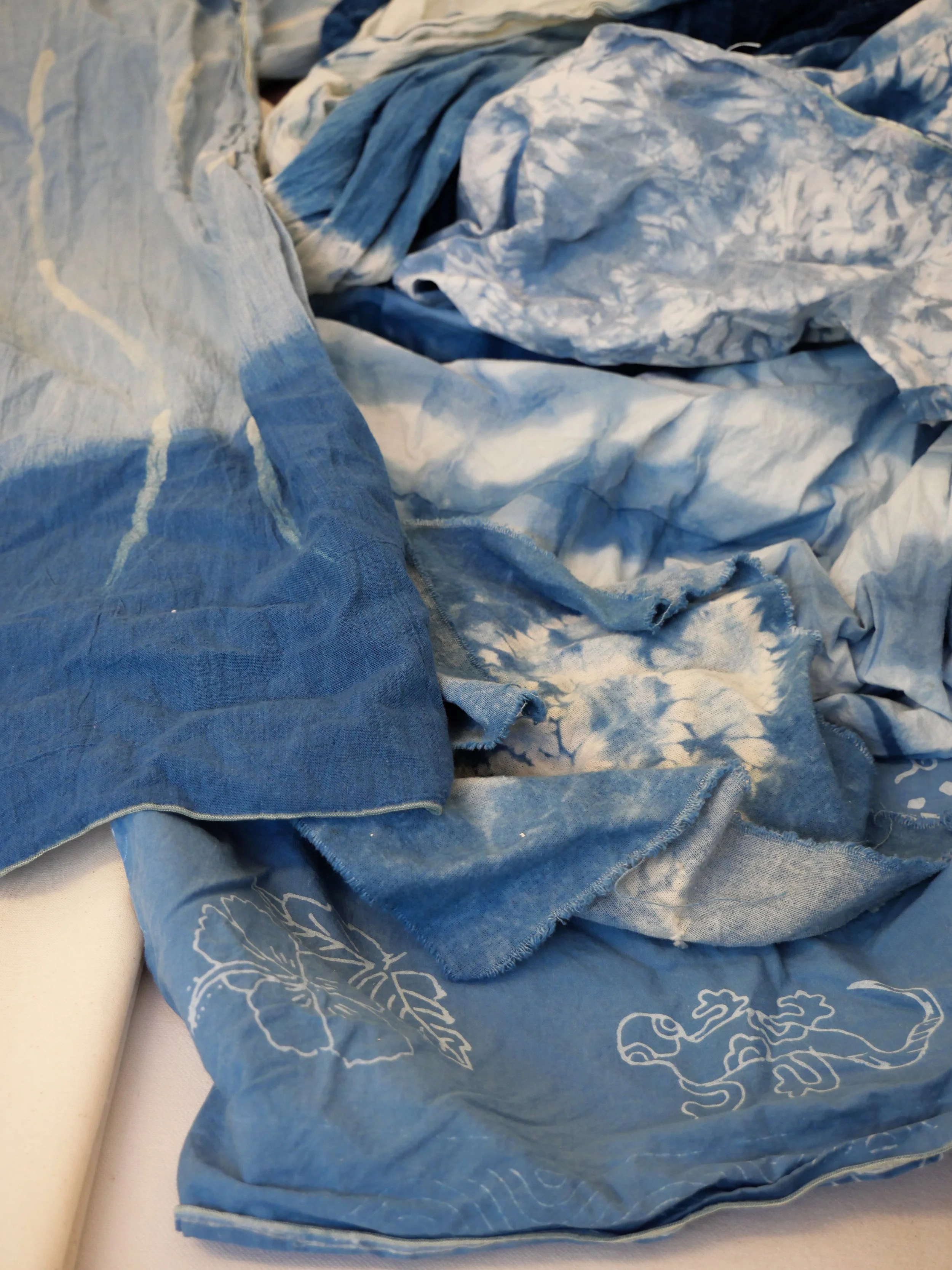 Une pile de tissus bleus avec des motifs de fleurs et de lézards, partie d'une caisse ou d'un meuble