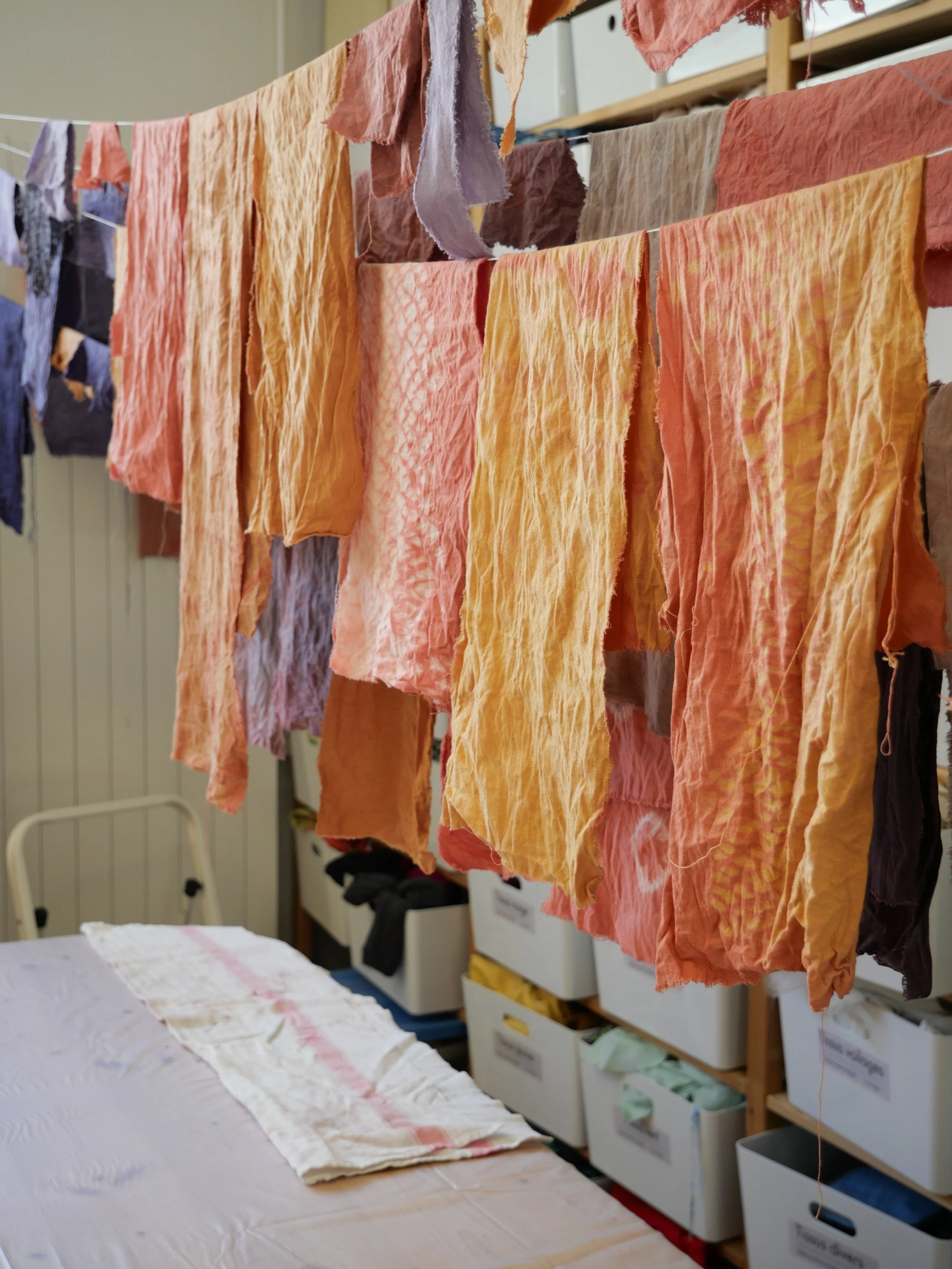 Linge coloré suspendu pour sécher, dans une buanderie ou atelier textile.