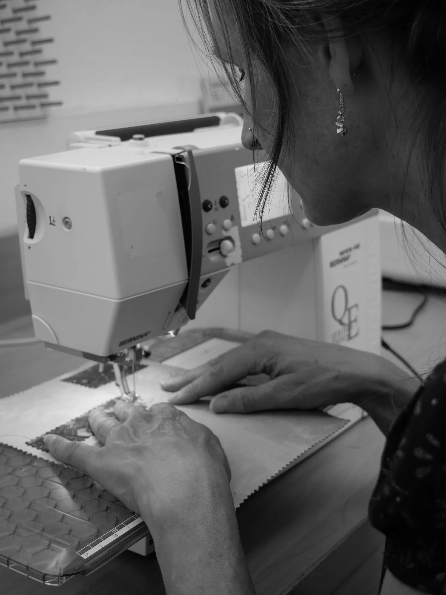 Une femme utilise une machine à coudre pour travailler sur un tissu.