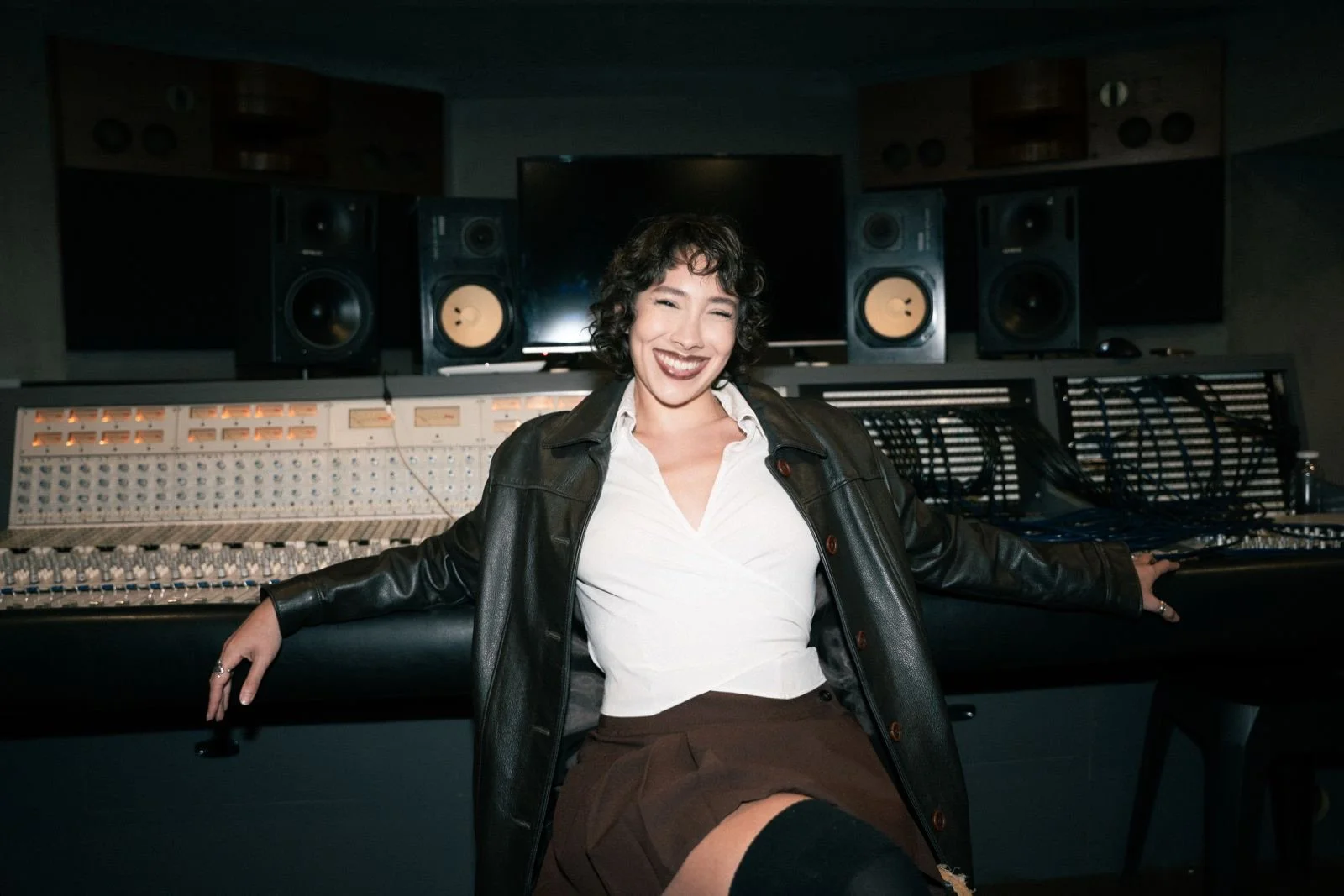 Mujer sonriendo en estudio de grabación con equipo de audio.