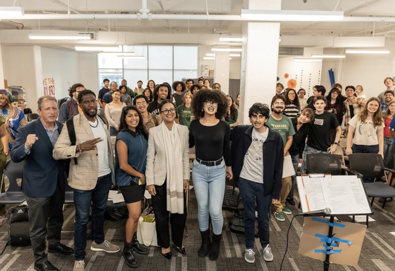 Livable Future Package NYC organizers in a room with white walls, ceiling lights, and a stand in the lower right.