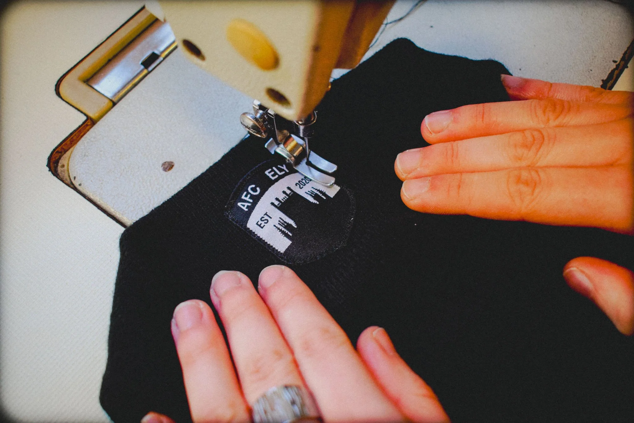 Attaching a brand label to fabric during the final garment finishing stage