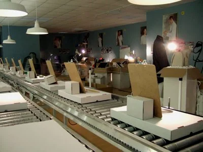 The show highlights included oversized angle poise lamps, a working 60 ft looping conveyor belt, bespoke folding cardboard structure