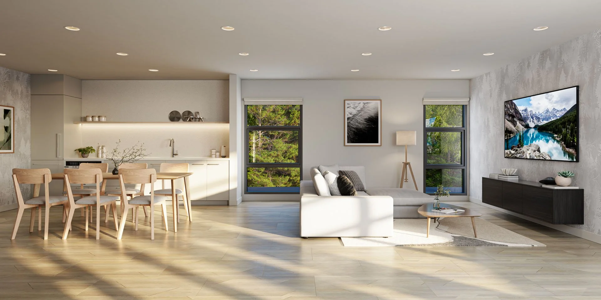 Modern open-concept living room and kitchen with light wood flooring, white walls, a white sofa, a wooden coffee table, and a wall-mounted TV. Large windows show a green outdoor view, and there is a dining area with wooden chairs and a table on the left.