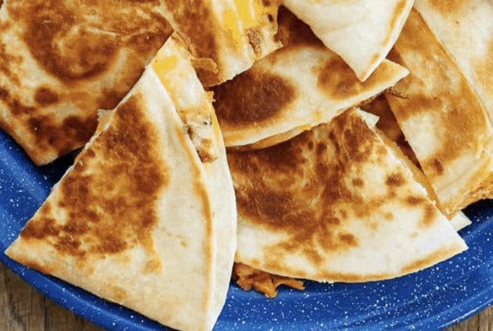 Close-up of several pieces of browned, toasted quesadillas on a blue plate.