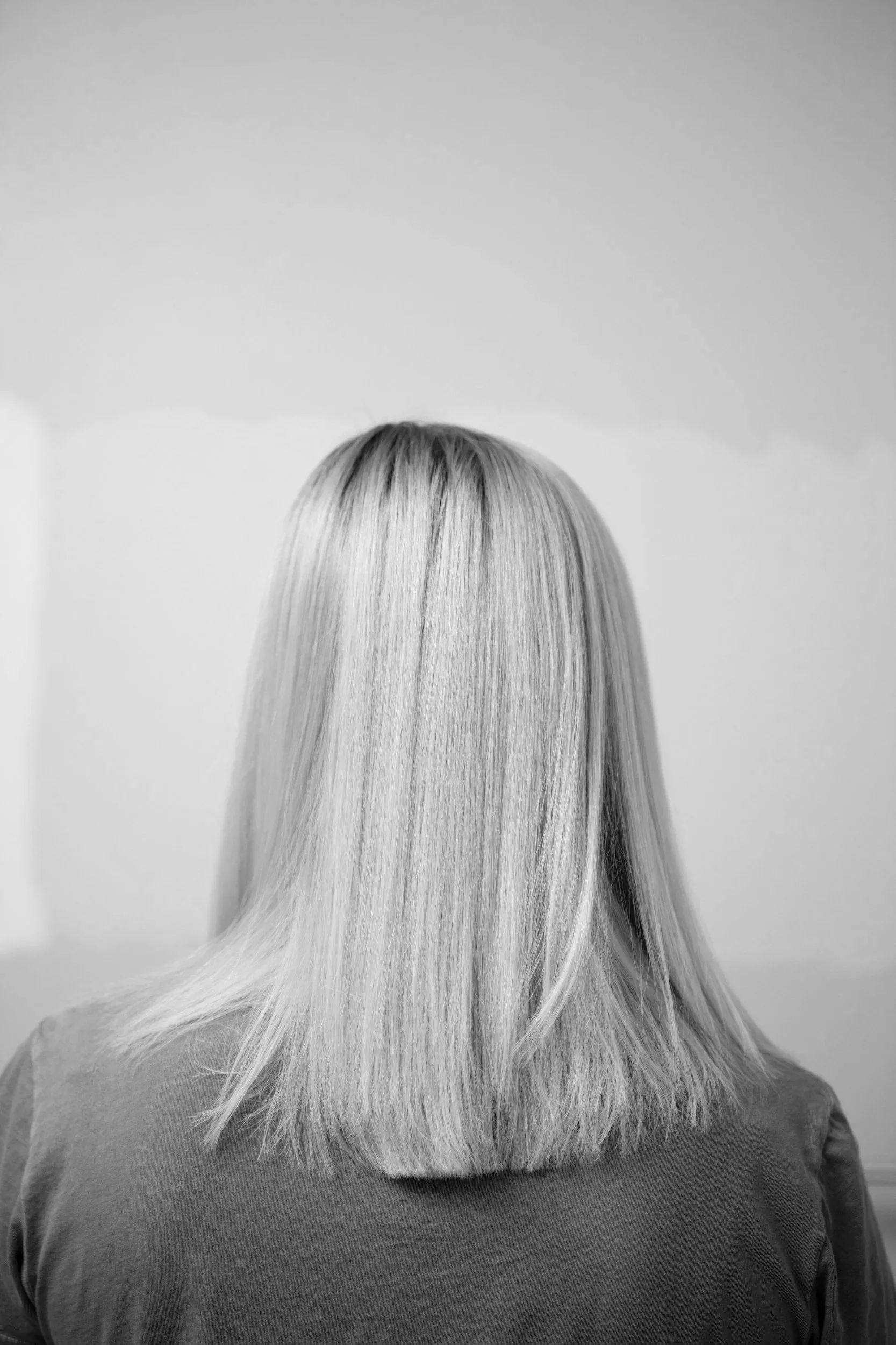 Black and white photograph of a person viewed from behind with long, straight, light-colored hair and wearing a shirt.