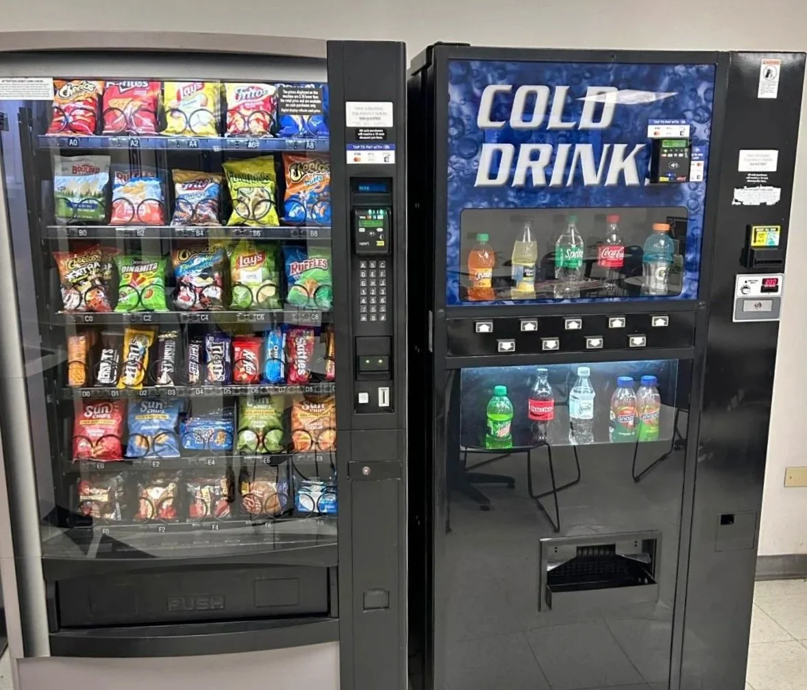 Vending machines, one selling snacks like chips and the other offering cold drinks such as soda and bottled water.