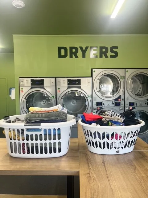 Clean laundry, neatly folded in laundry basket on nice timber folding tables at Blenheim laundromat
