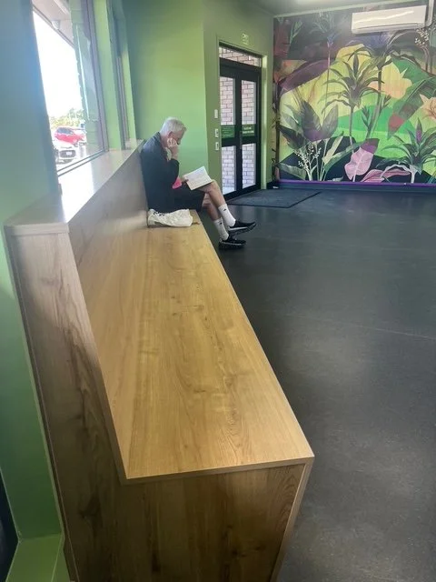 Customer relaxing on beautiful timber seating and reading a book while his laundry is washing and drying