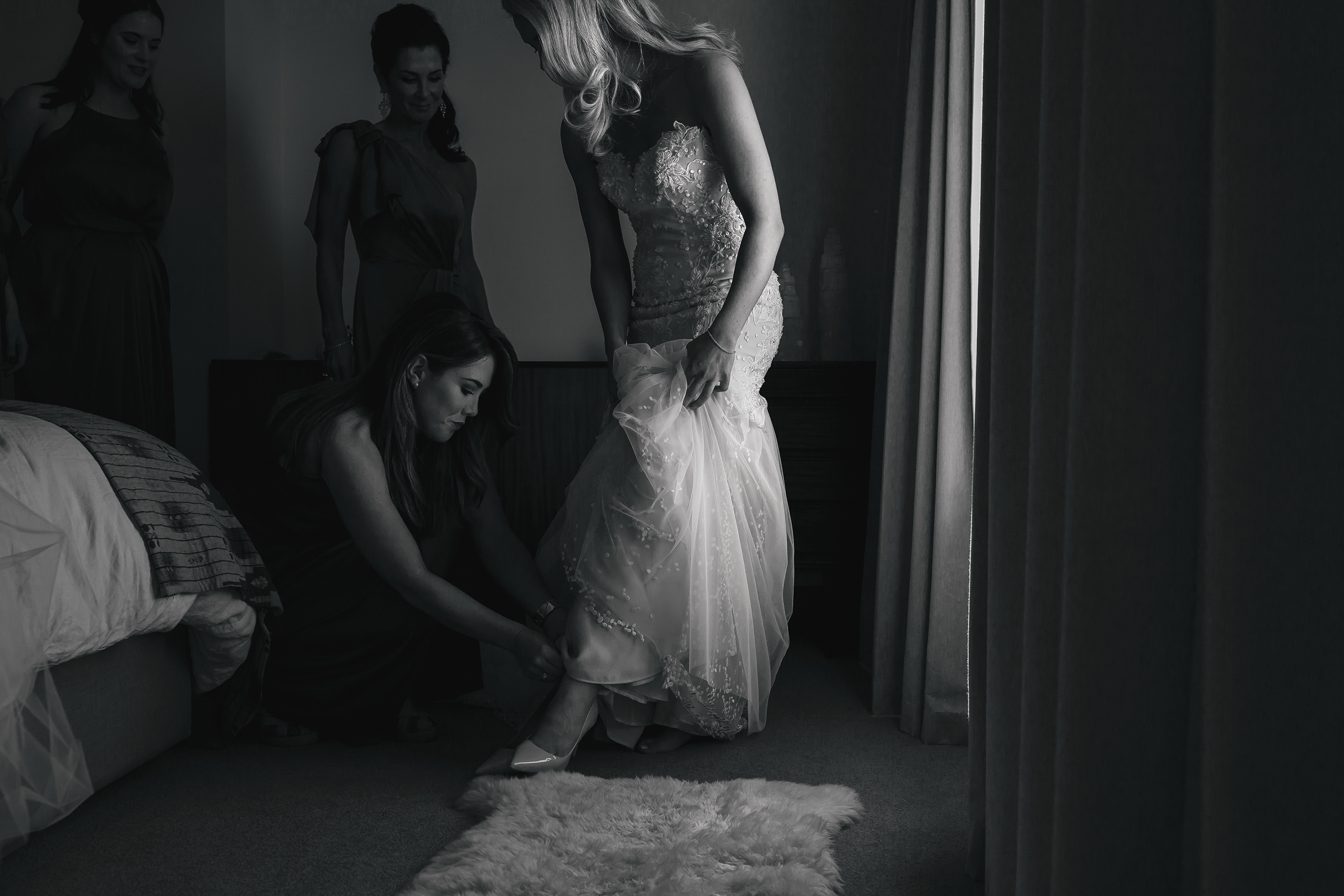 Bridesmaid helping bride put shoes on
