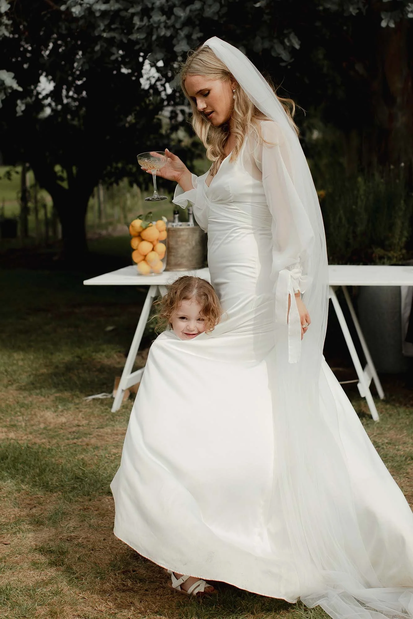 Child wrapped in brides dress