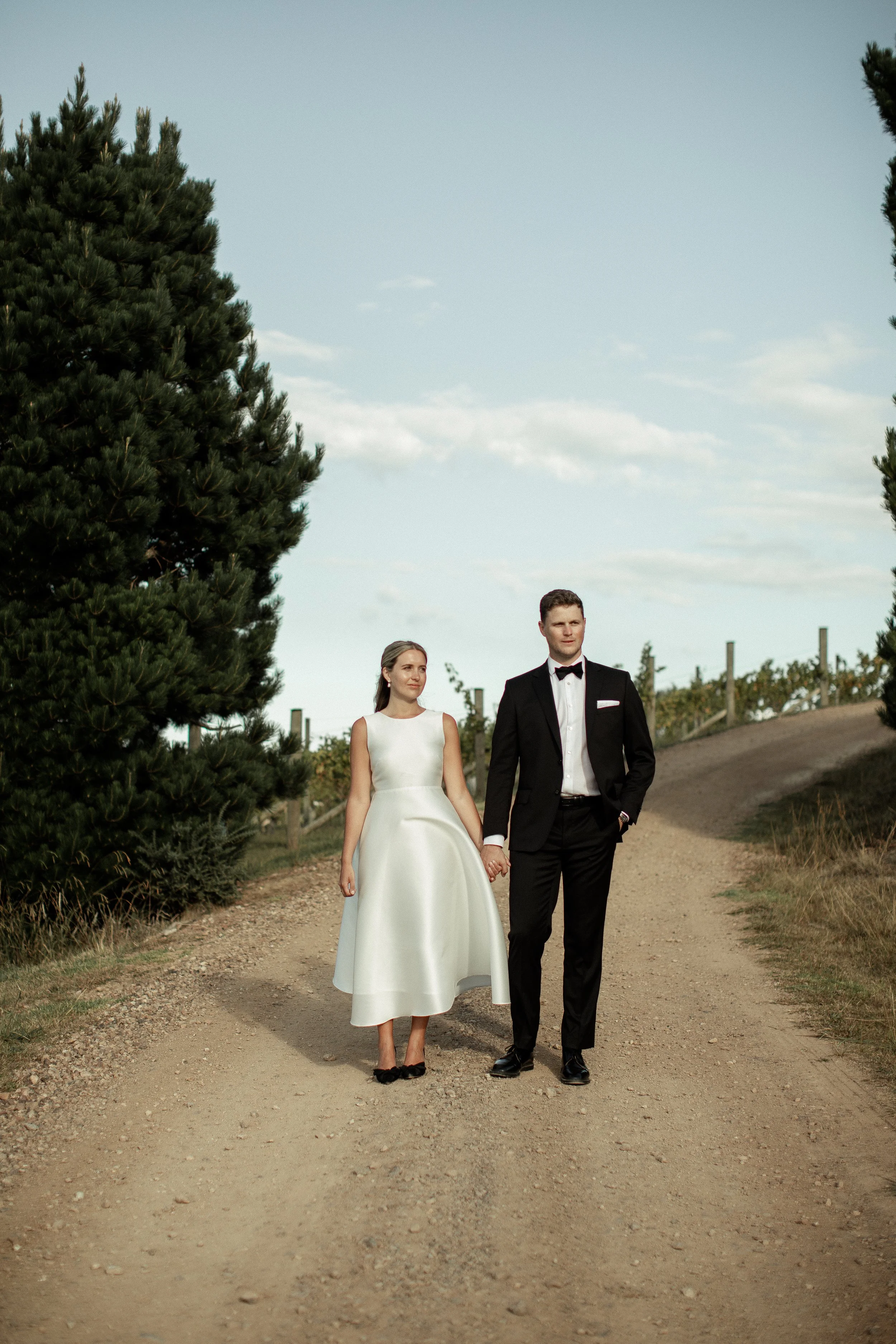 Bride and groom standing by the poplar tress on Waiheke