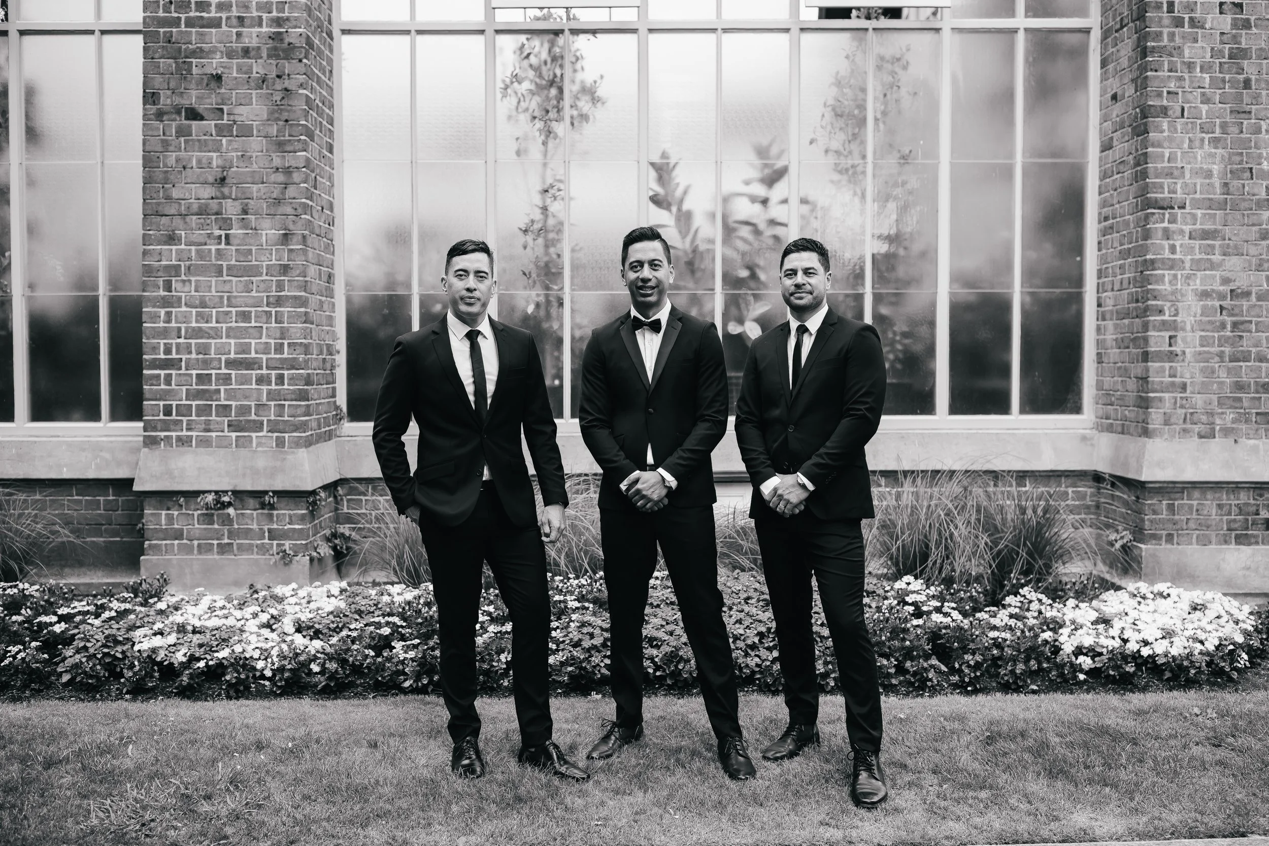 Groom and groomsmen standing outside a glasshouse