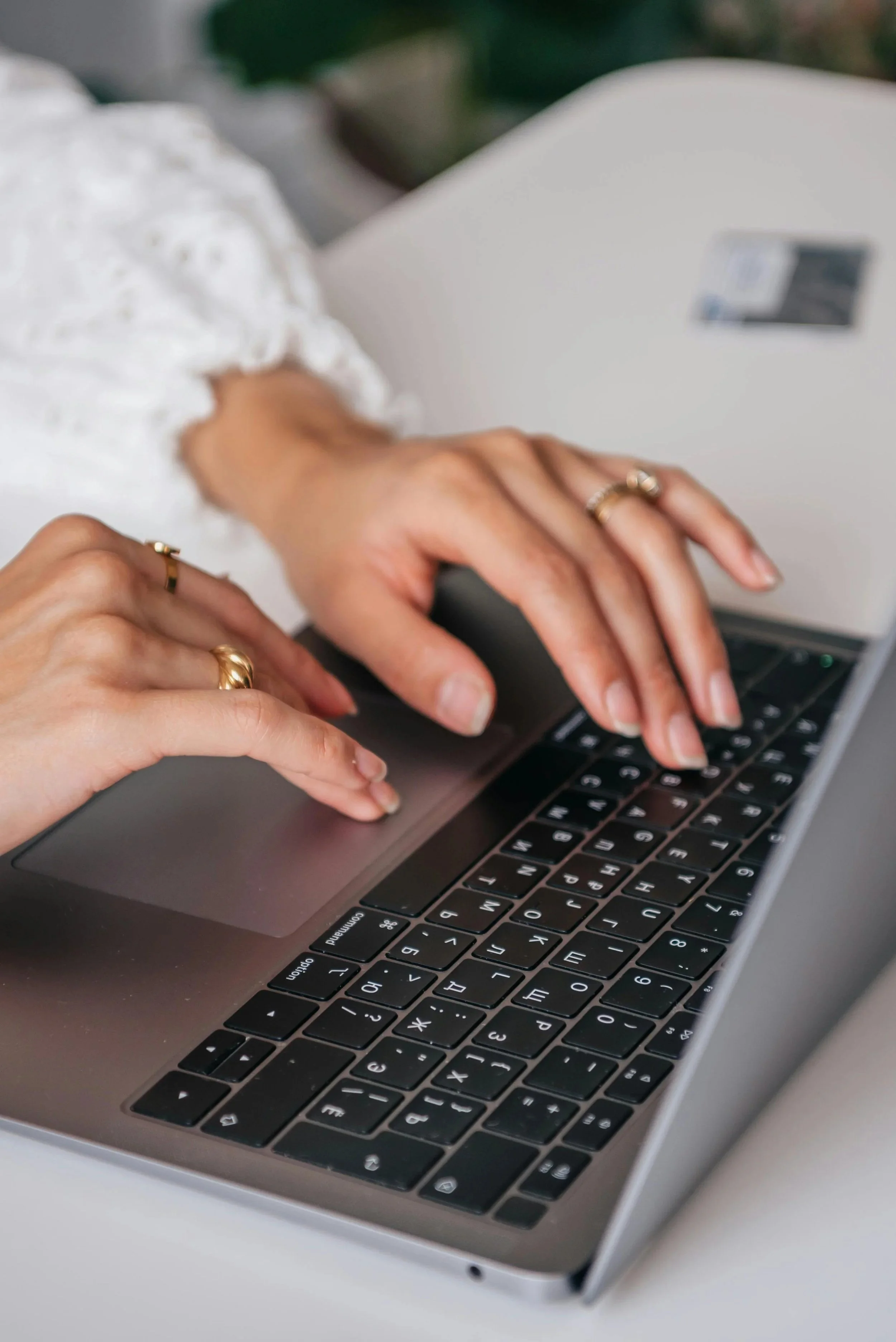 Person typing on a laptop keyboard with rings on their fingers.
