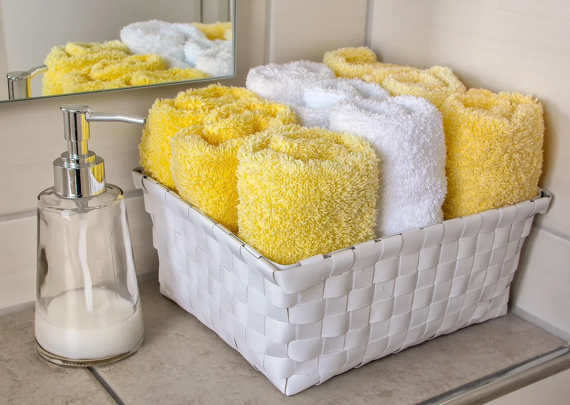Bathroom vanity with organized hand towels in white basket and nearby soap dispenser