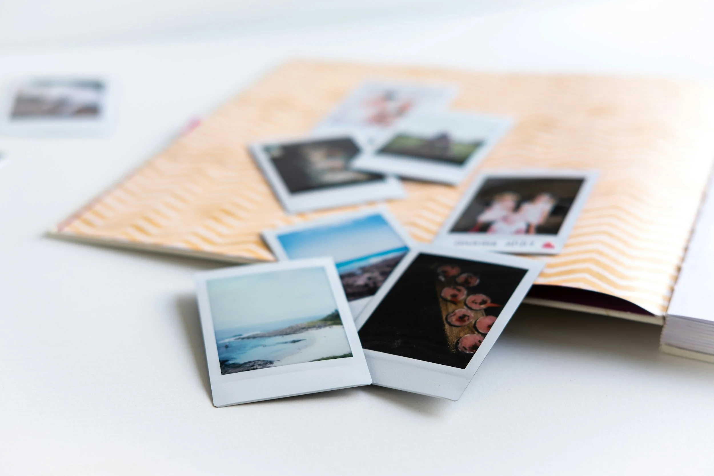 A collection of printed photographs scattered on a light-colored, striped paper surface.
