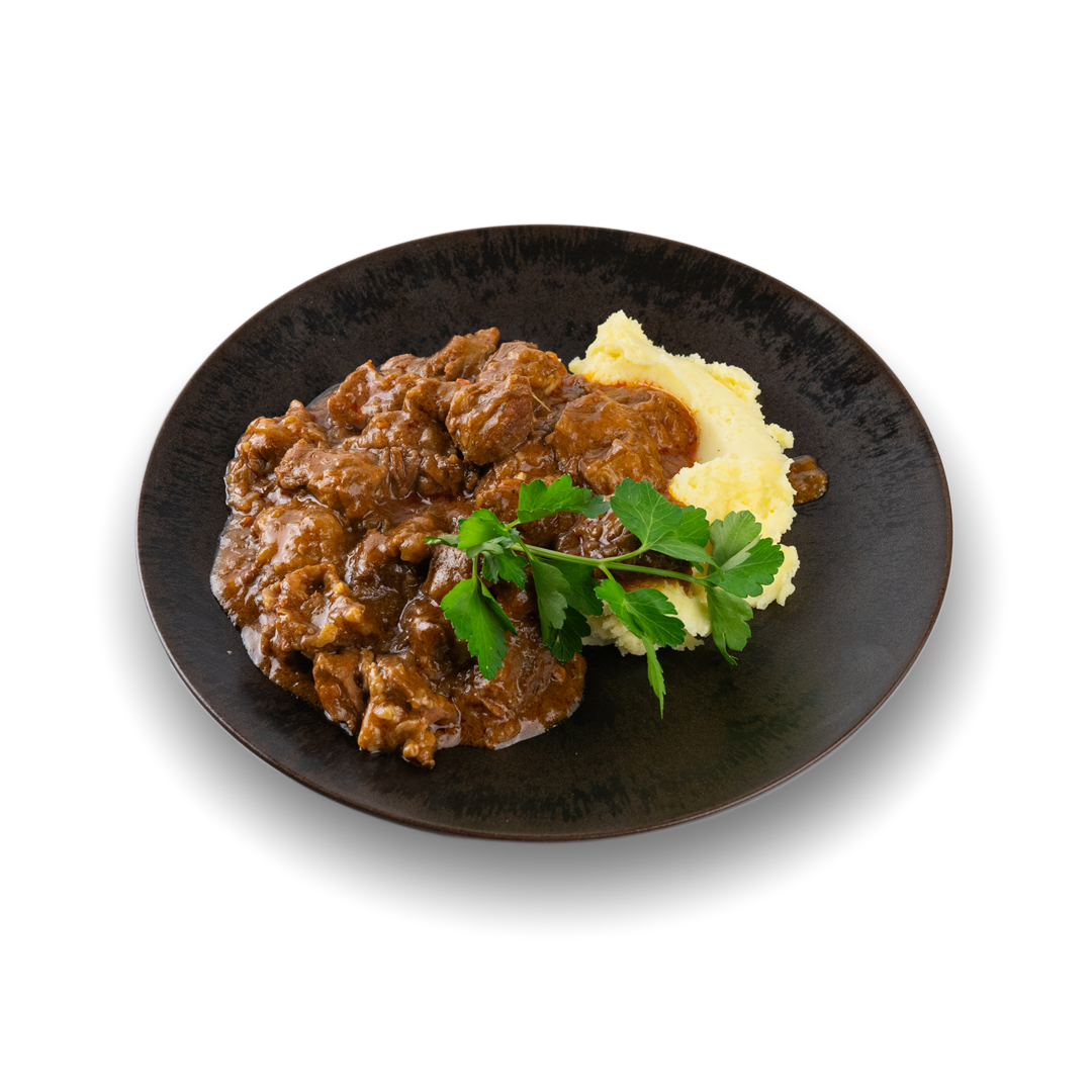 Rindergulasch mit Kartoffelpüree und Petersilie auf einem schwarzen Teller