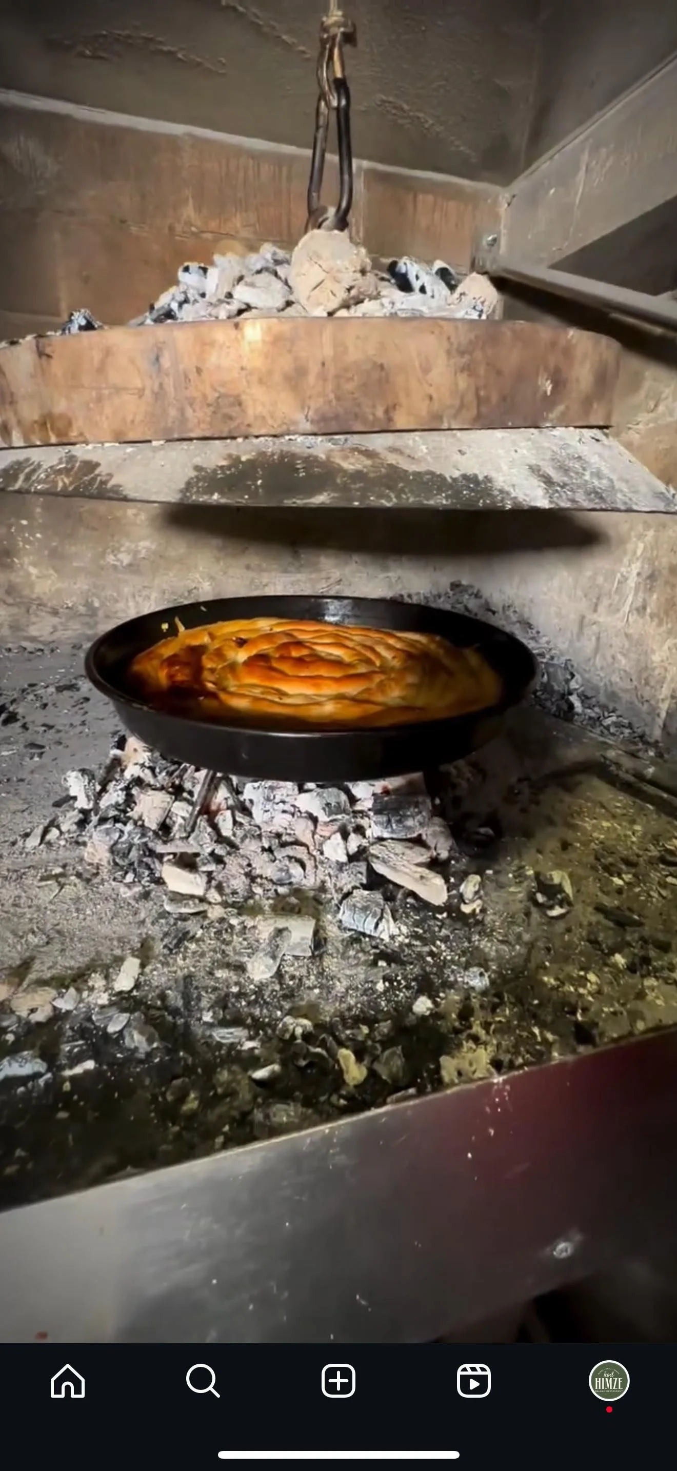 Ein Holzofen mit einem Pizzastein, auf dem eine Pizza im Ofen backt.