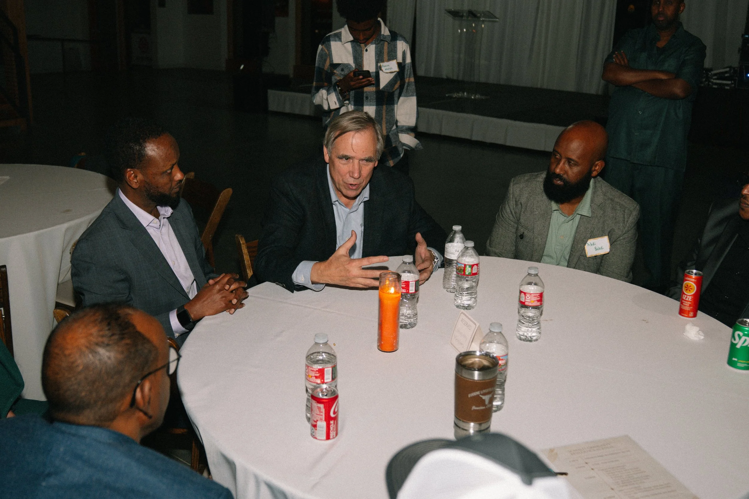 Senator Jeff Merkley seated with a group of males representing numerous African organizations & communities. 