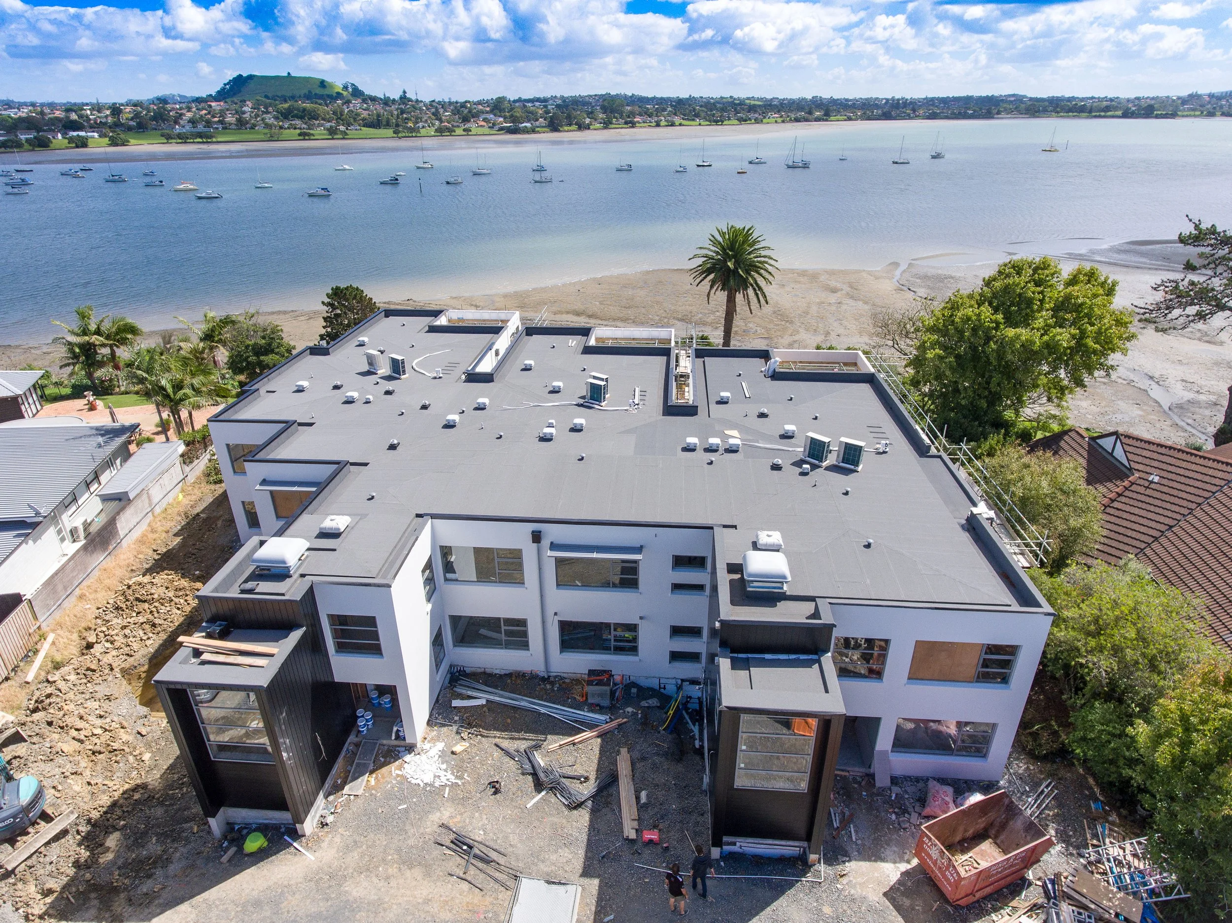 Aerial view of coastal multi-unit residential development with flat roof waterproofing, Auckland