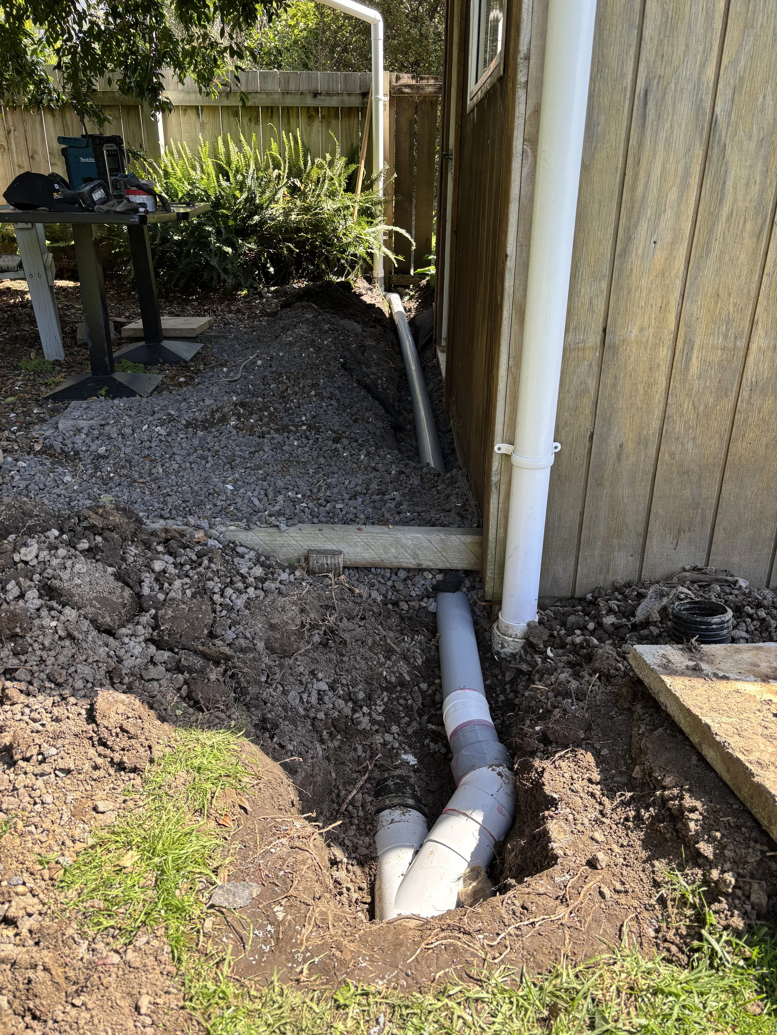 Close-up of a person fixing a water pipe under a sink with a wrench and plumber's tape.