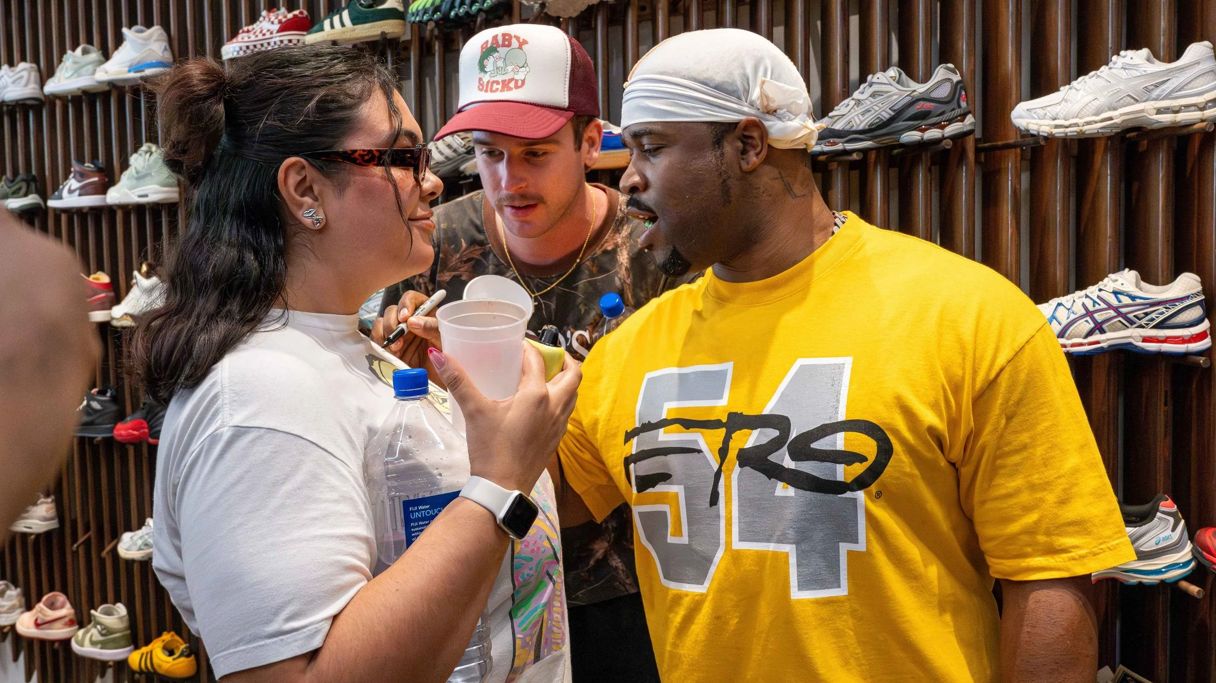 Three people engaged in a heated discussion inside a sneaker store, with shelves of athletic shoes in the background.