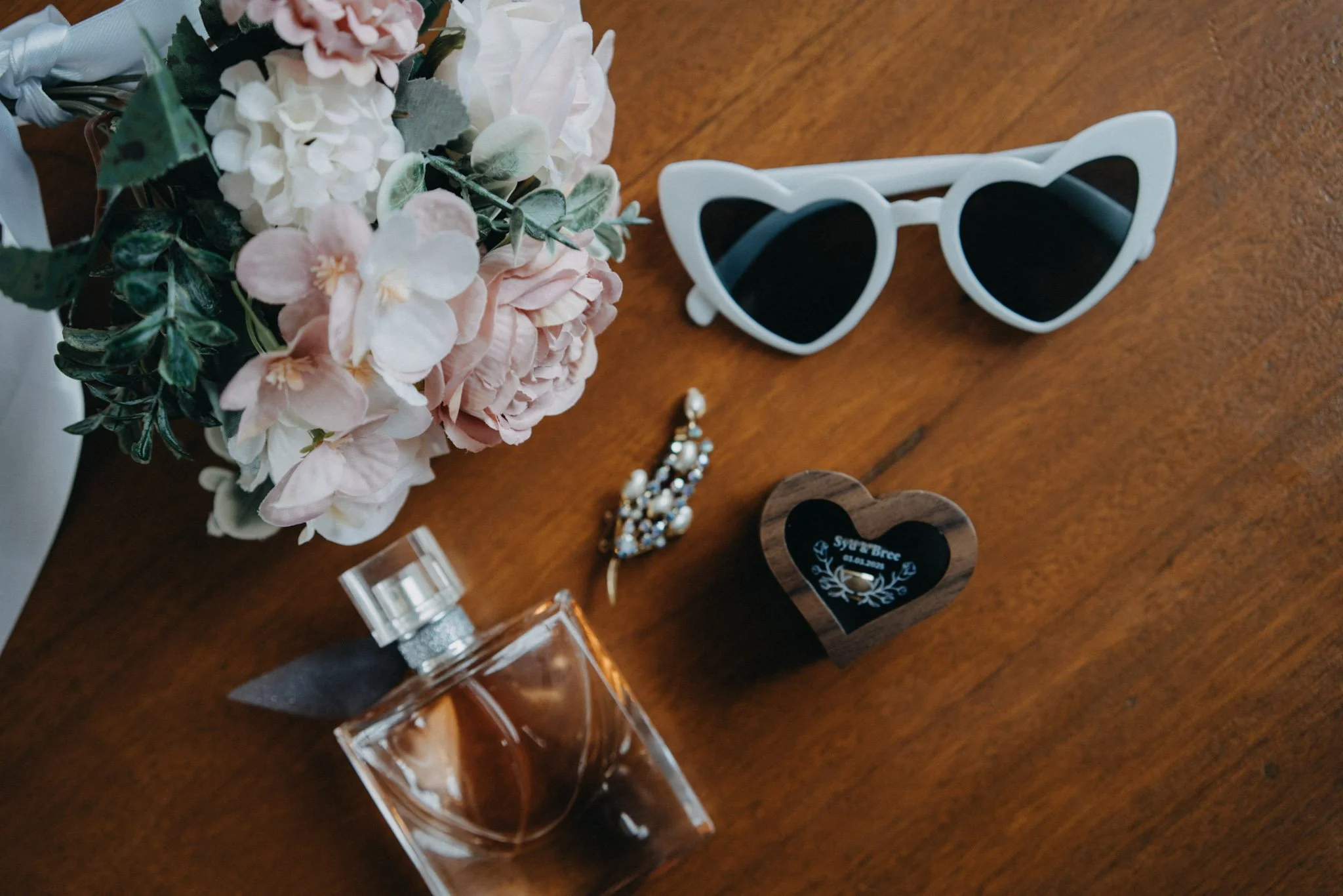 Bridal details with rings, perfume and flowers photographed in Maleny
