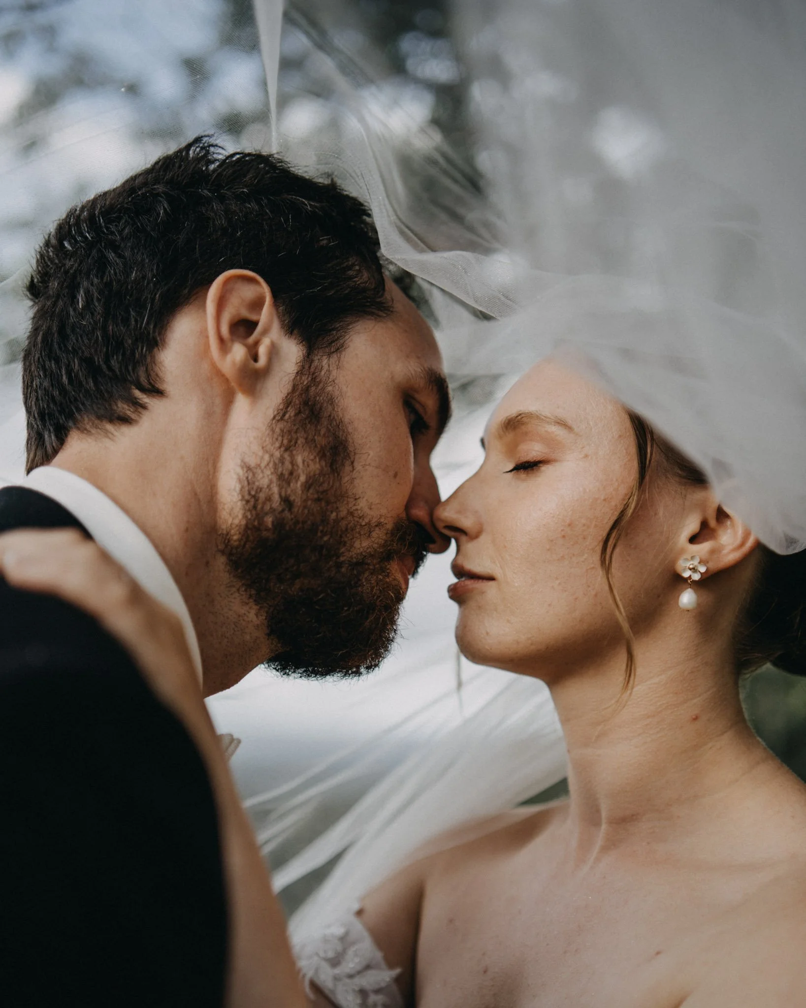 Bride and groom kiss under veil in Maleny